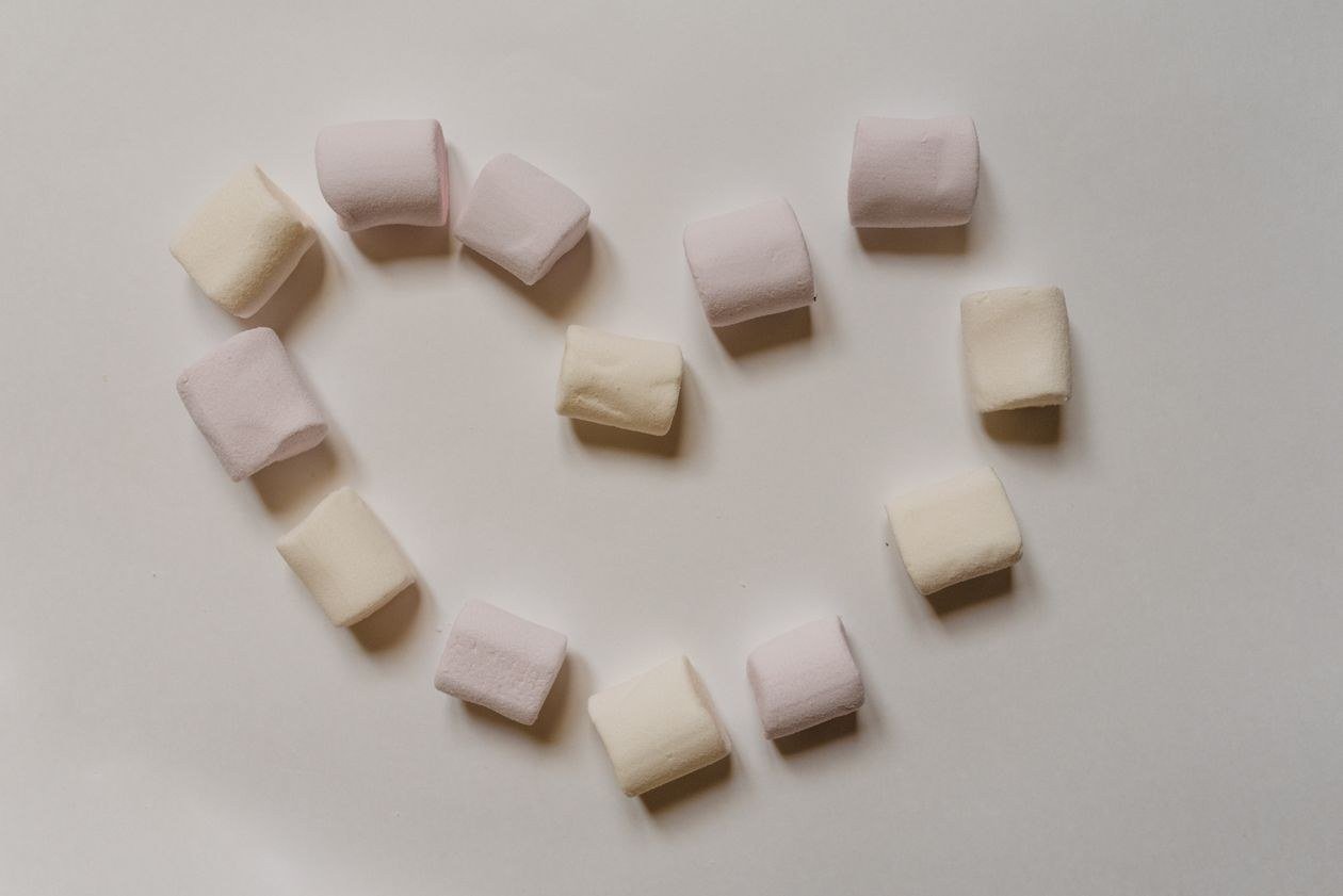 Top view arrangement of white marshmallows placed on a white table in the shape of a heart