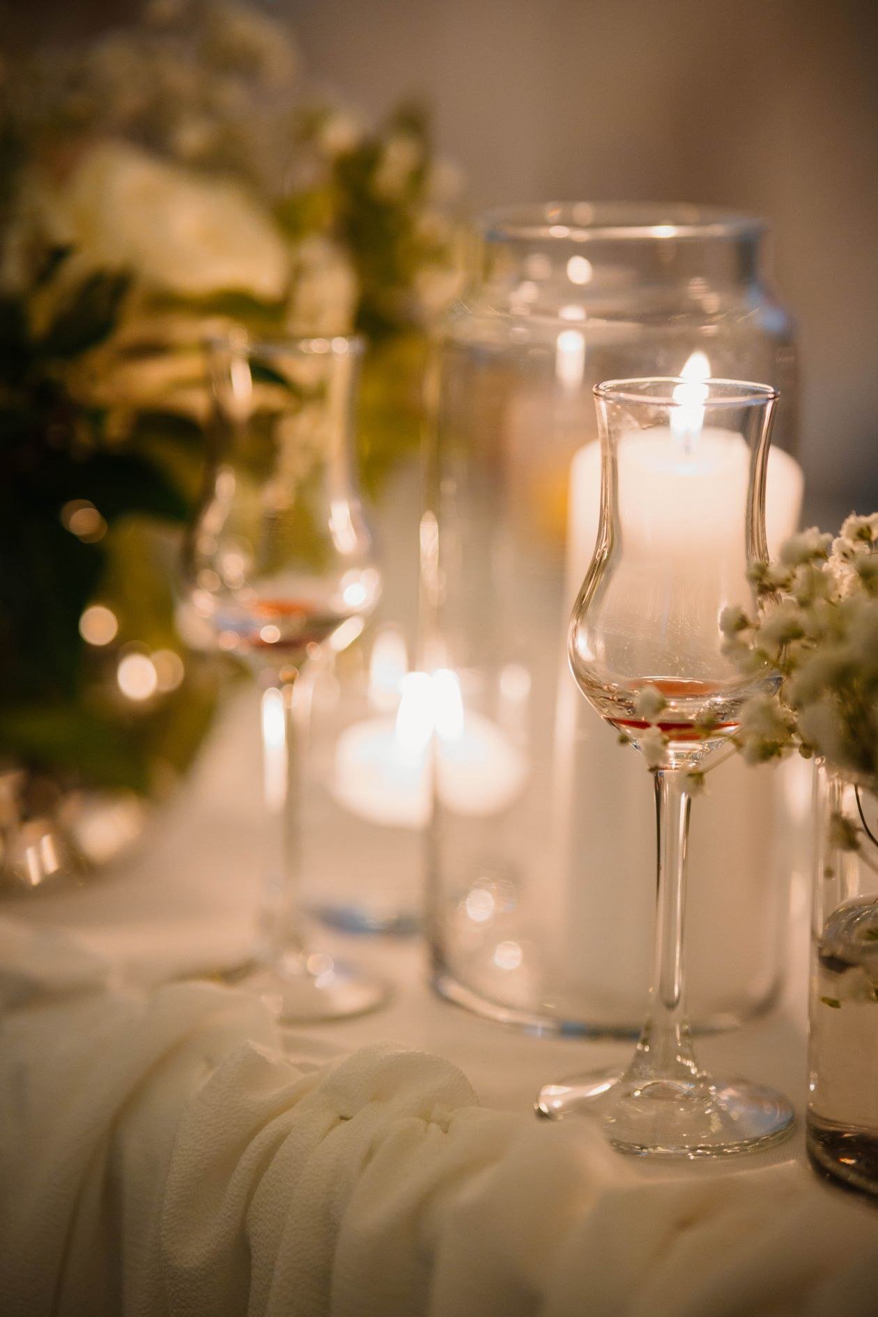 A softly lit romantic setting with candles and floral arrangements creates a warm and elegant ambiance