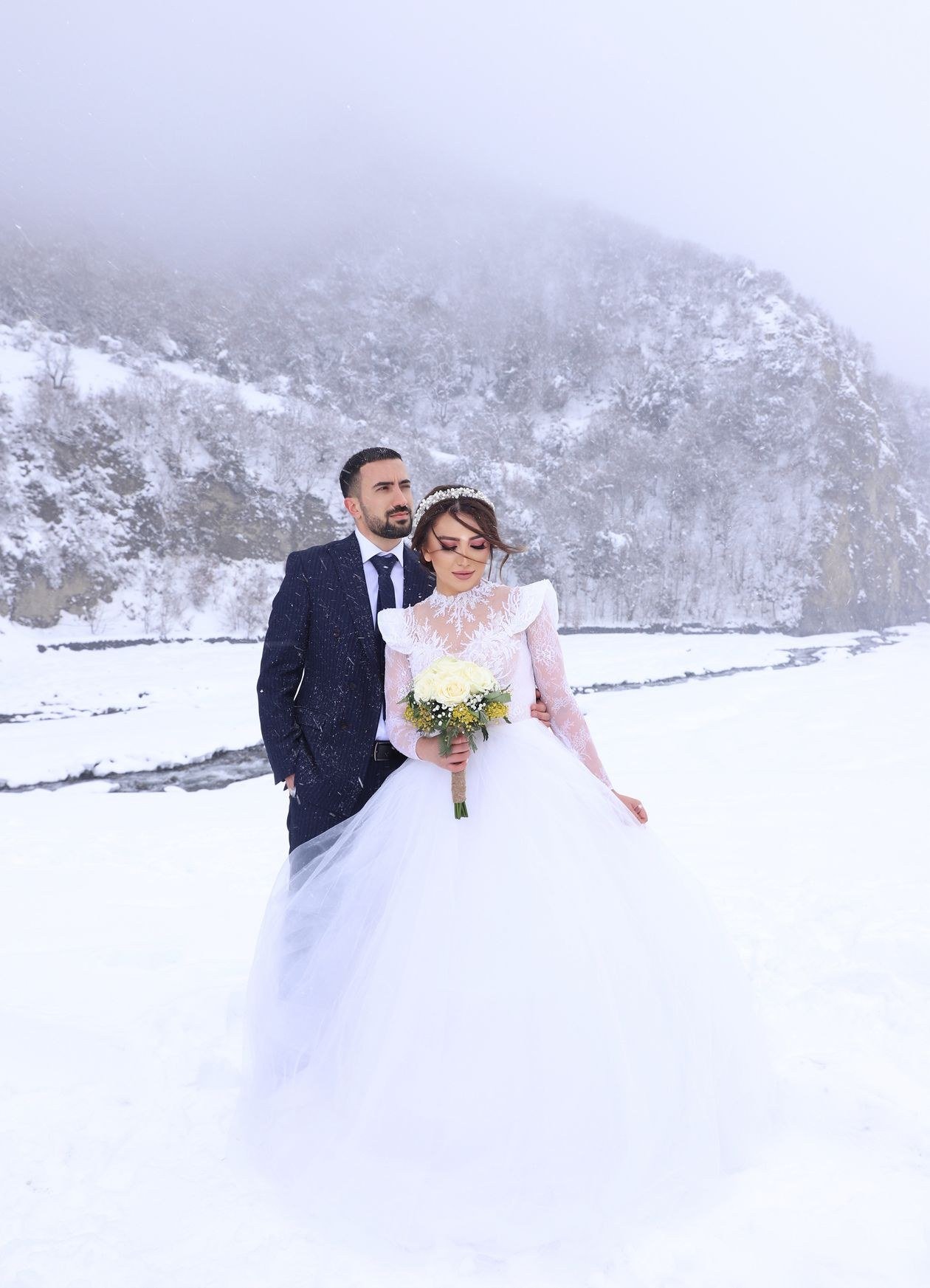 Bride and groom pose beautifully in a snowy mountain setting, capturing a romantic winter wedding scene