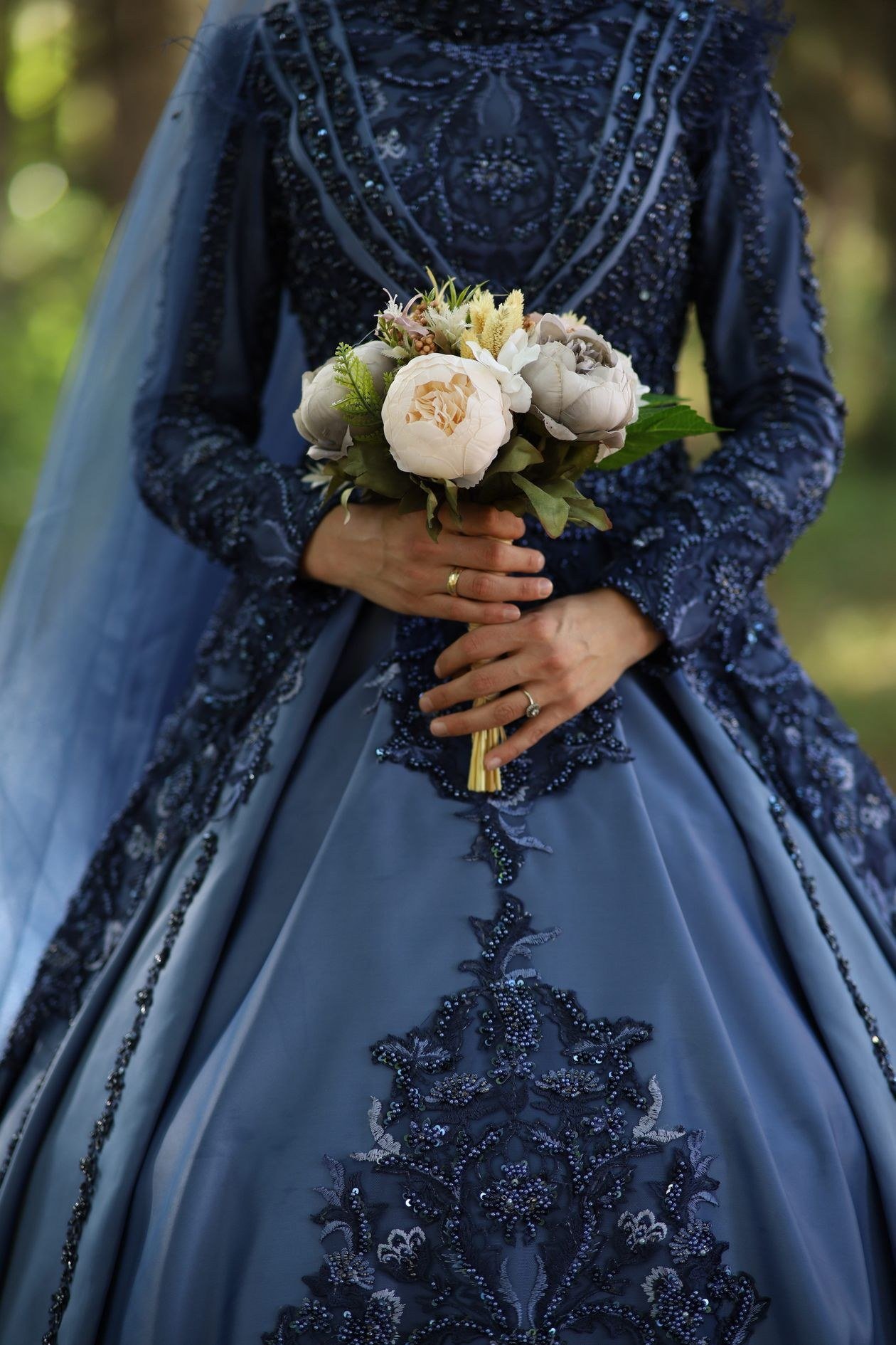 Bride in intricately designed blue gown holding a floral bouquet