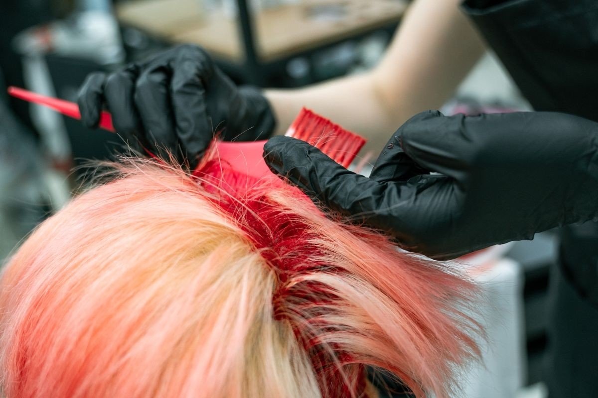 Pink hair dye streaks through dark hair