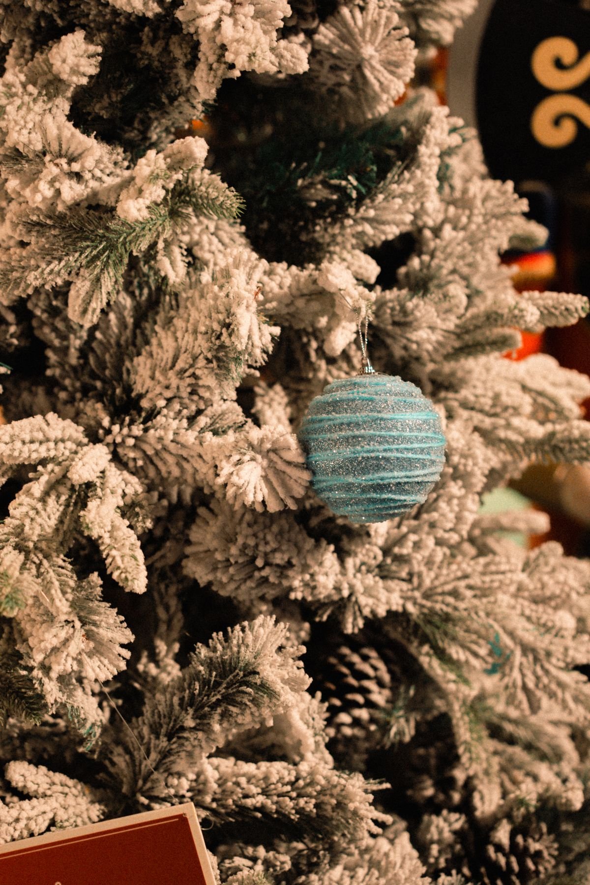 Gold star tree topper on top of a flocked Christmas tree with snowy branches