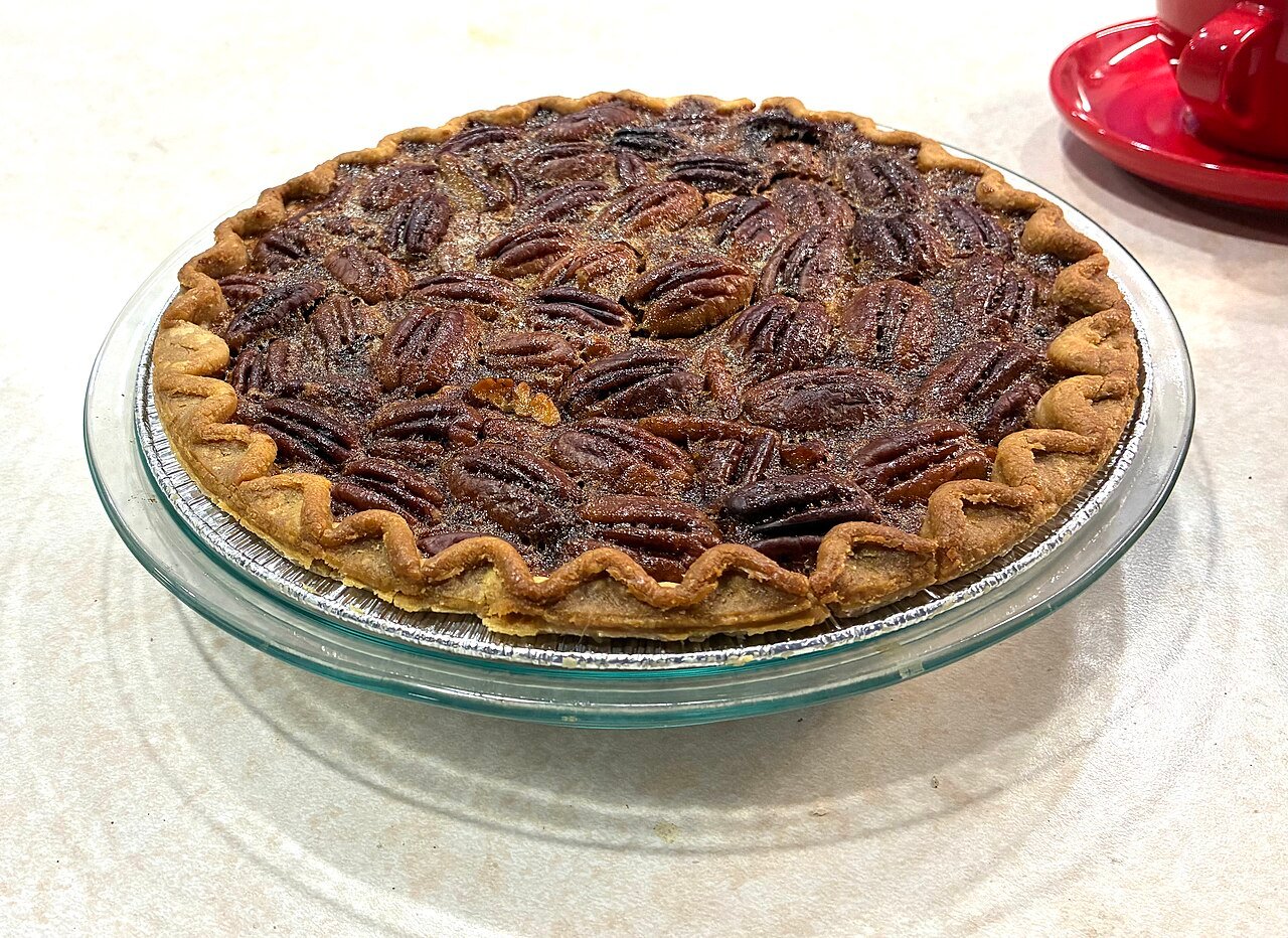 Pouring glossy caramel glaze over the top of pecan pie cake