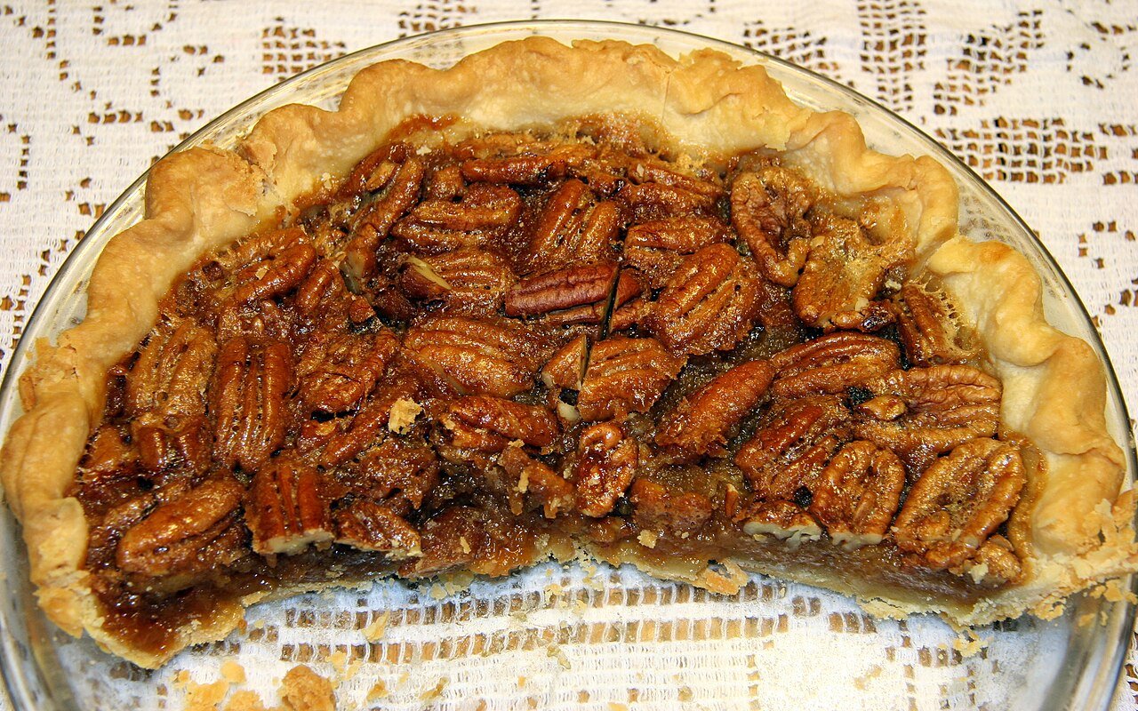 Decorating pecan pie cake top with whole toasted pecans in a circular pattern
