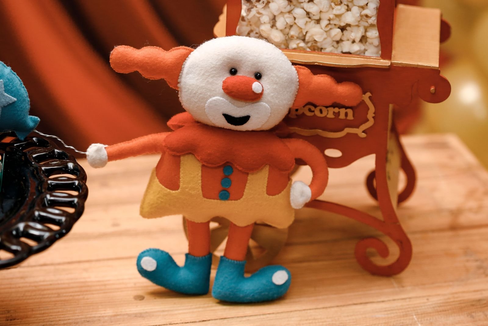 Vibrant clown doll toy on wooden table with popcorn stand party decor