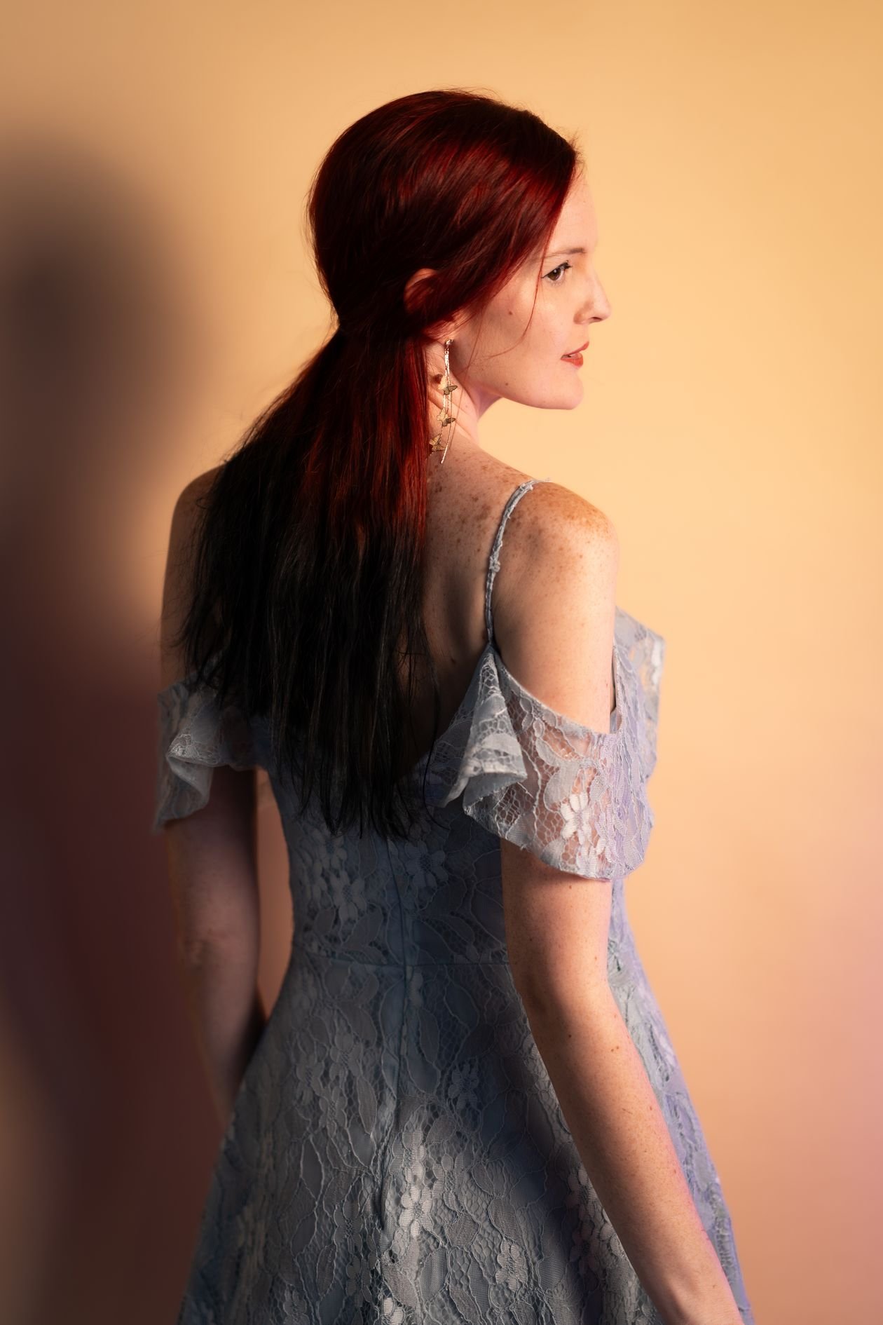 Back view of red-haired woman in blue lace dress indoors