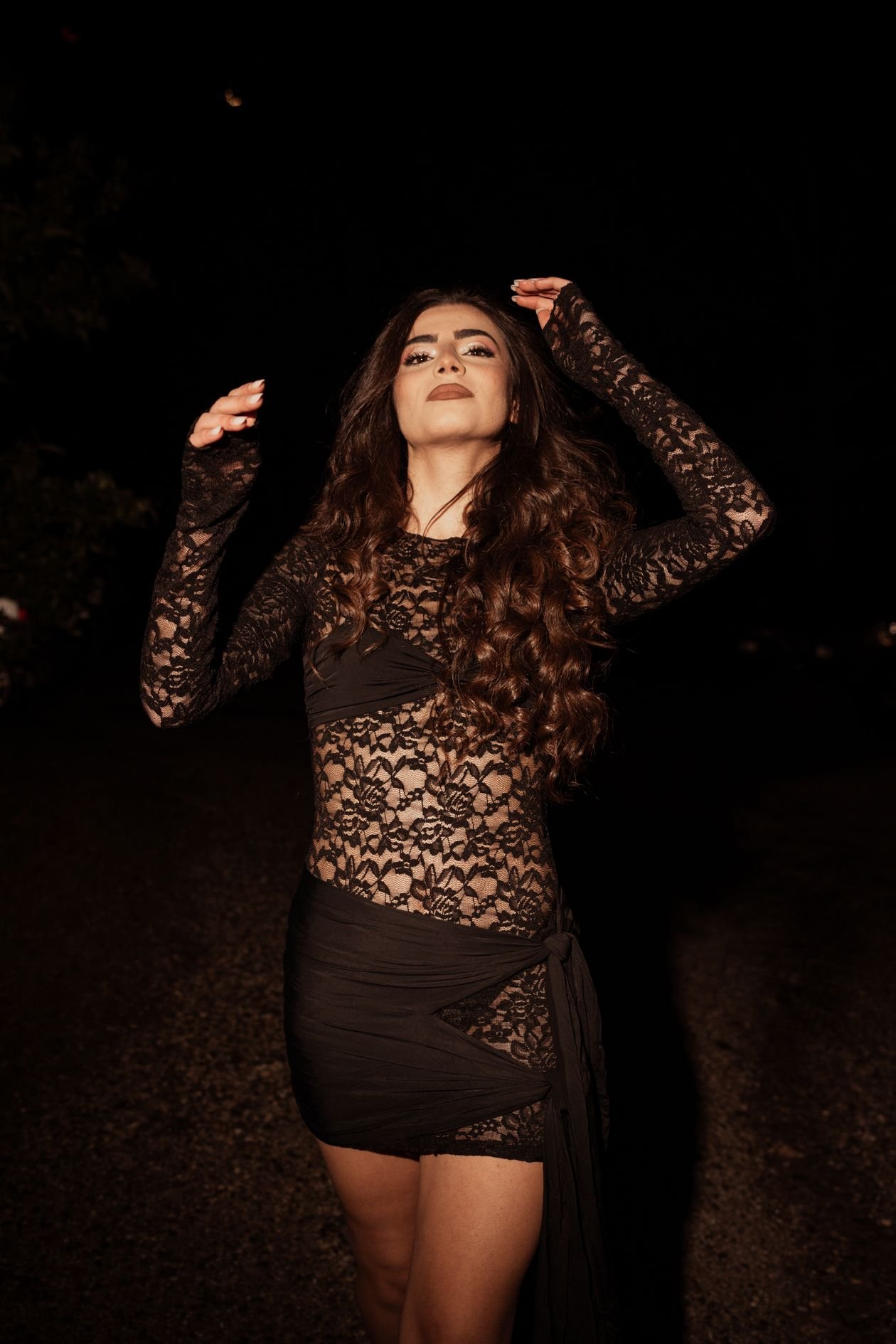 Woman in black lace dress under nighttime lighting