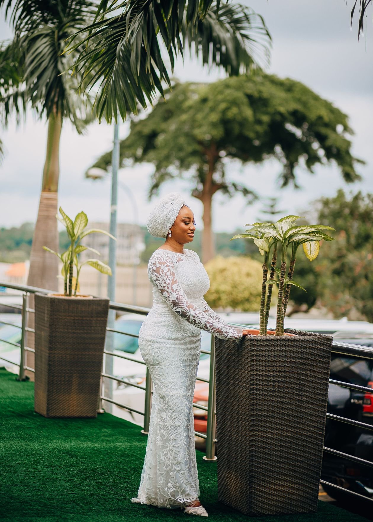 Woman in white lace dress outdoors near palm trees