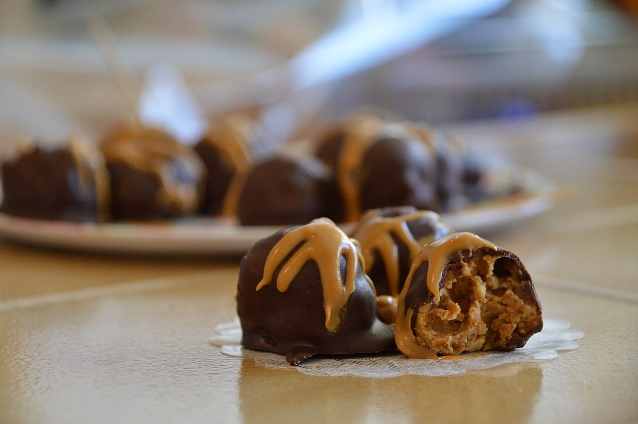 Rolling peanut butter mixture into smooth even balls on parchment paper