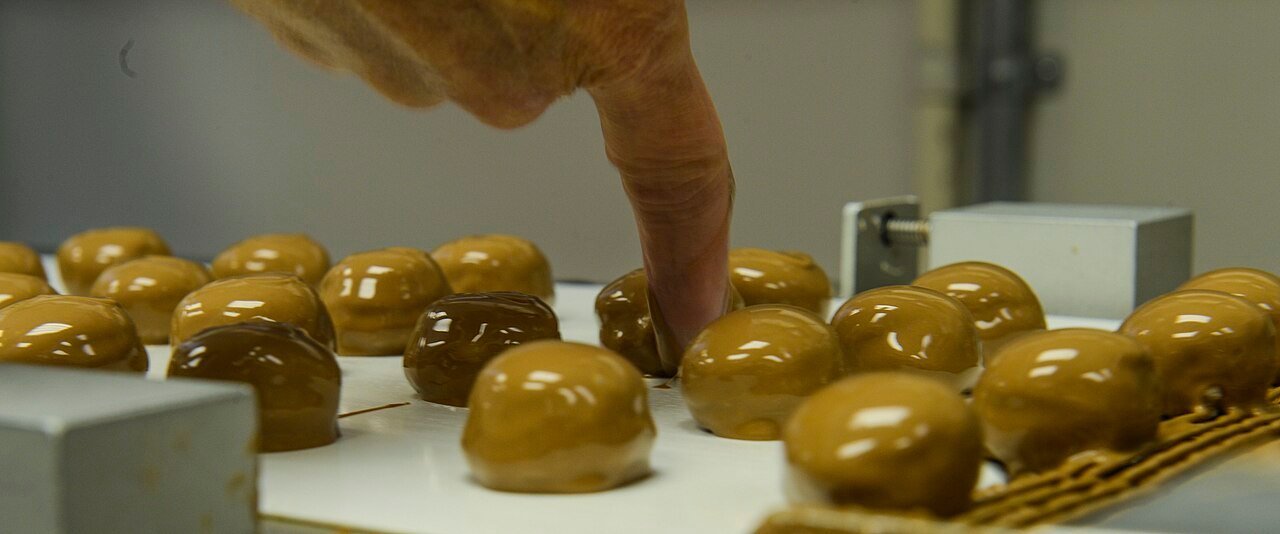 Dipping frozen Butterfinger balls into melted chocolate with a fork