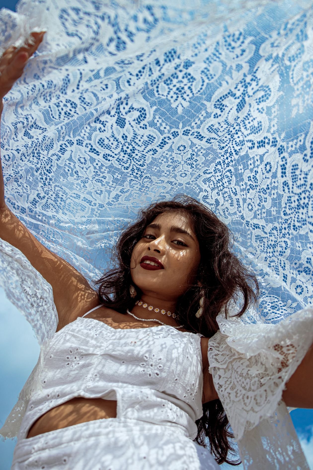Woman holding a large white lace scarf, fabric detail