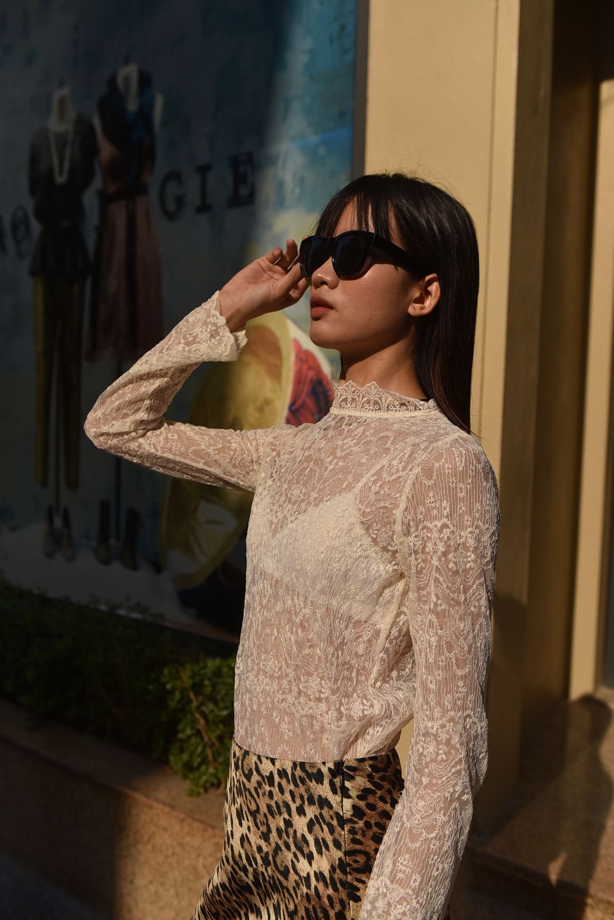 Woman in white lace blouse with leopard print skirt and sunglasses
