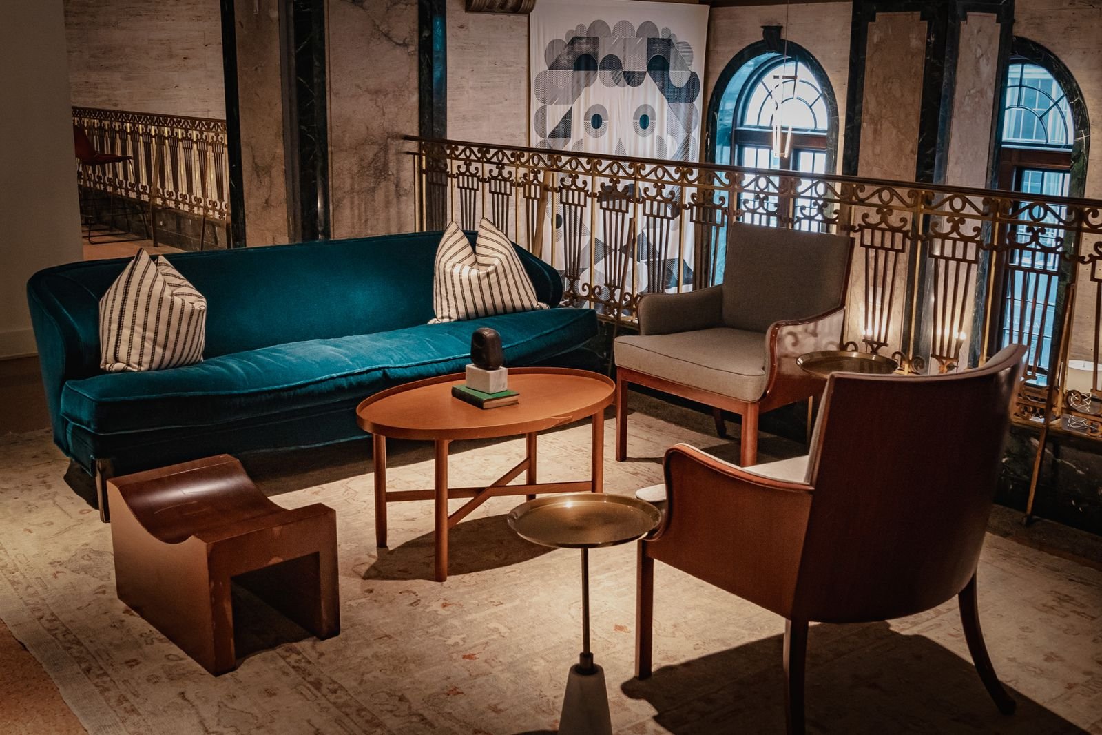 Stylish interior with vintage furniture, teal velvet sofa, and wooden chairs in warm light