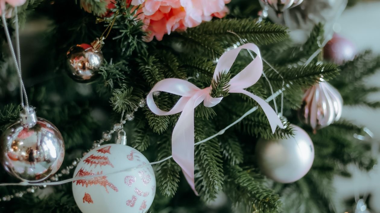 Christmas tree decorated with ornaments and a pink ribbon