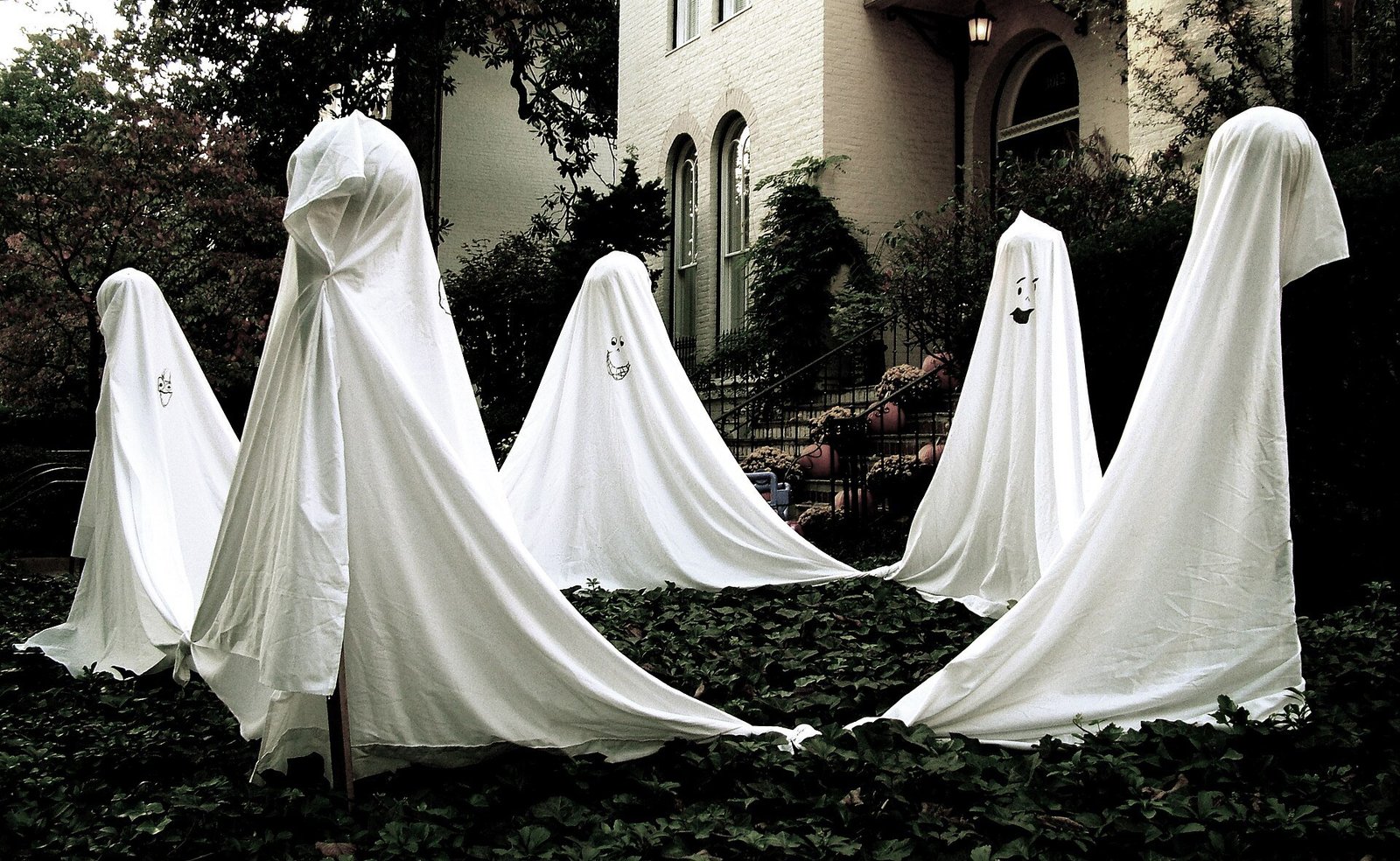 DIY tomato cage ghost ideas combined with pumpkins and tombstones in a haunted yard