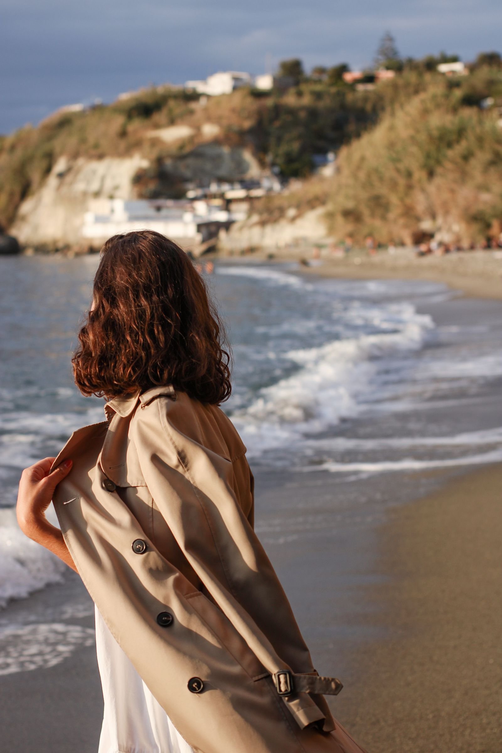 Woman in beige coat on sandy beach wearing cape style