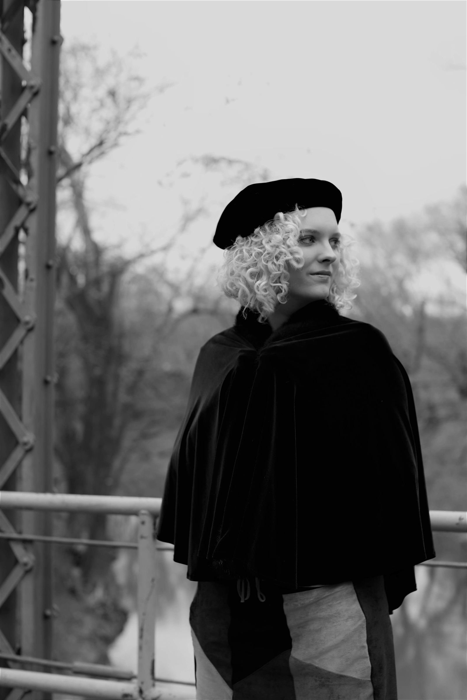 Fashionable woman in cape and beret on bridge retro style