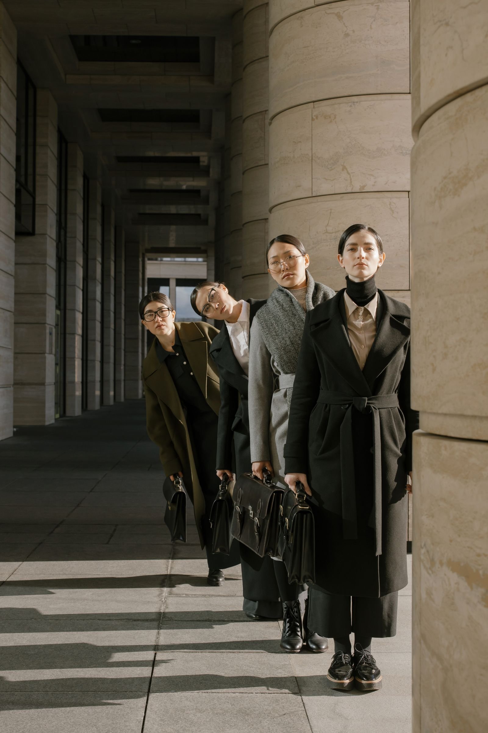Businesswomen in corporate attire wearing tailored cape coats outdoors