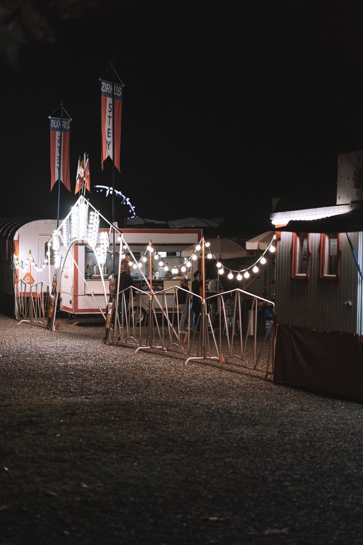 Backyard decorated as vintage midway with string lights and striped tents