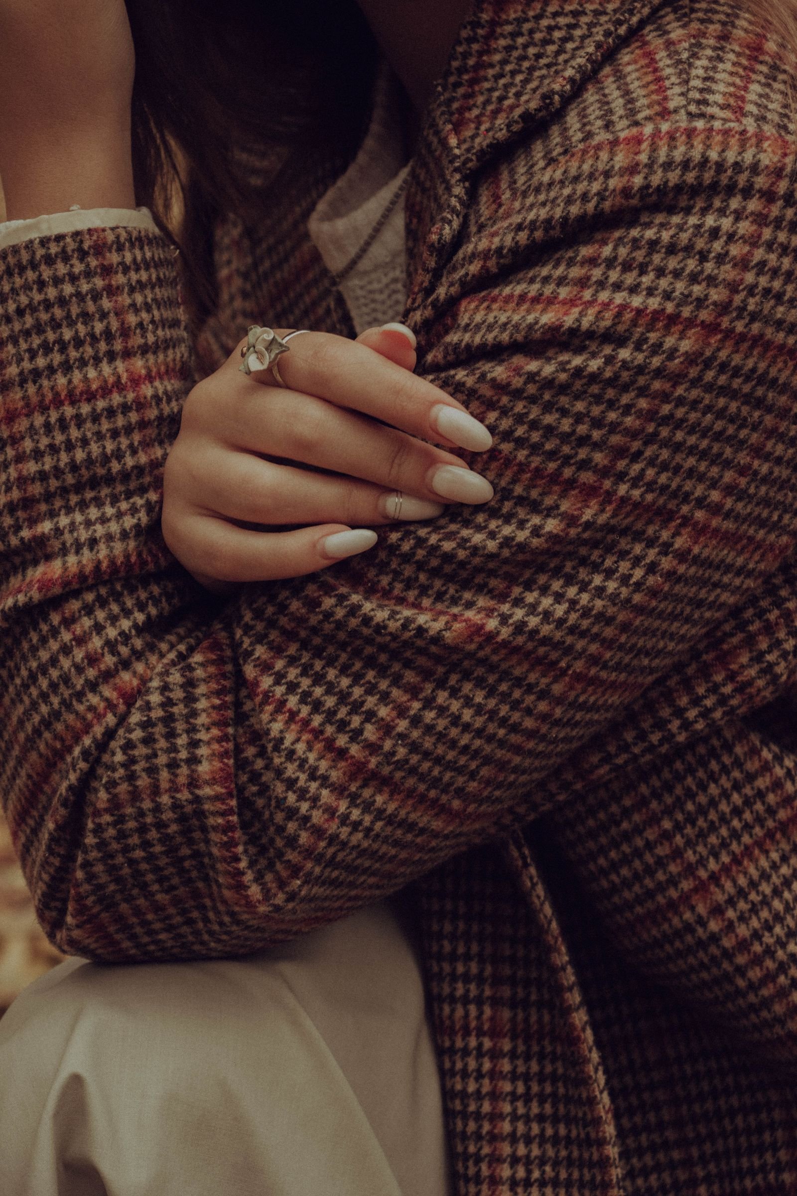 Close up of checkered blazer with manicured hand resting on the lapel