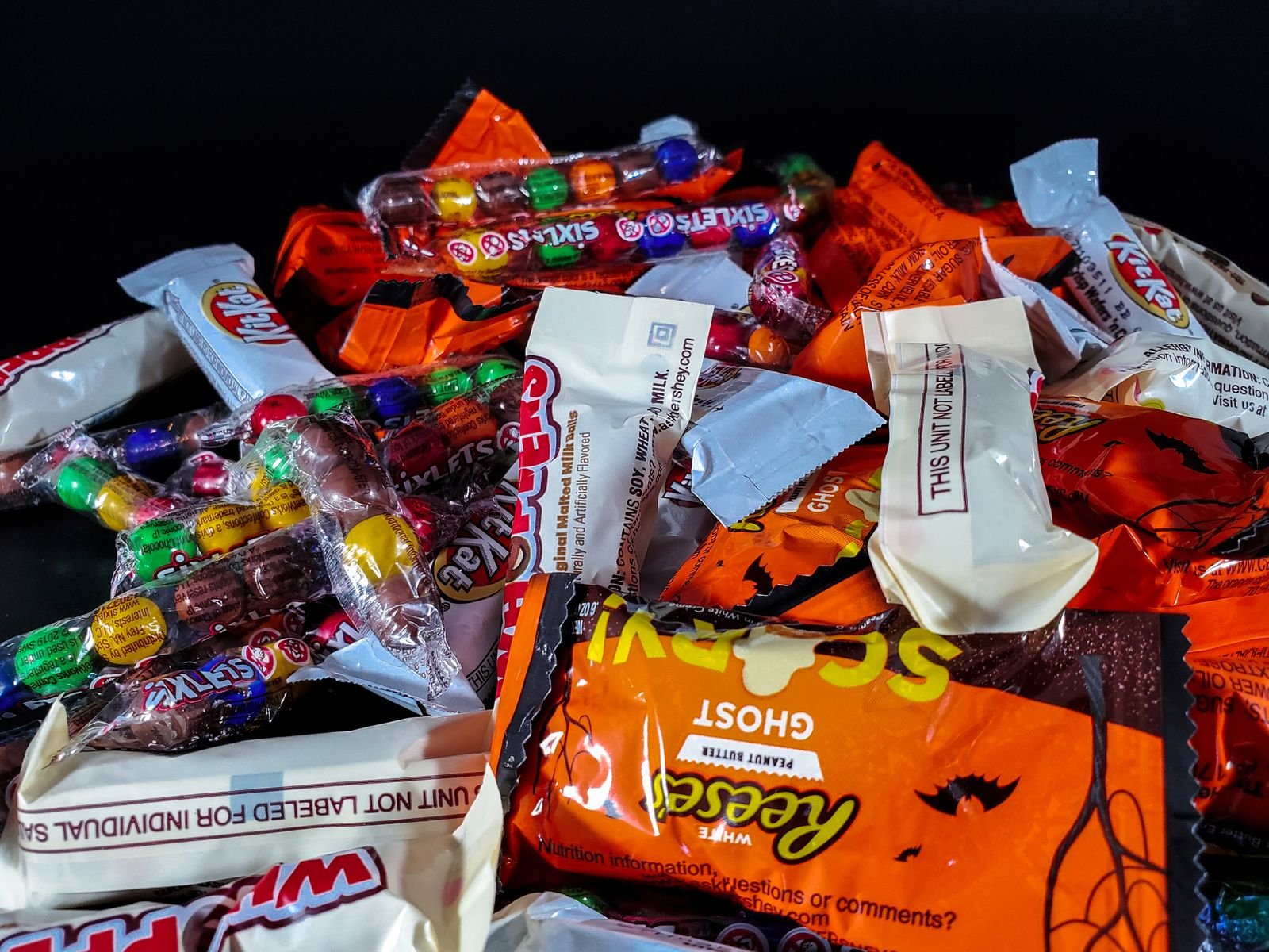 Paper treat bags painted like candy corn filled with Halloween sweets