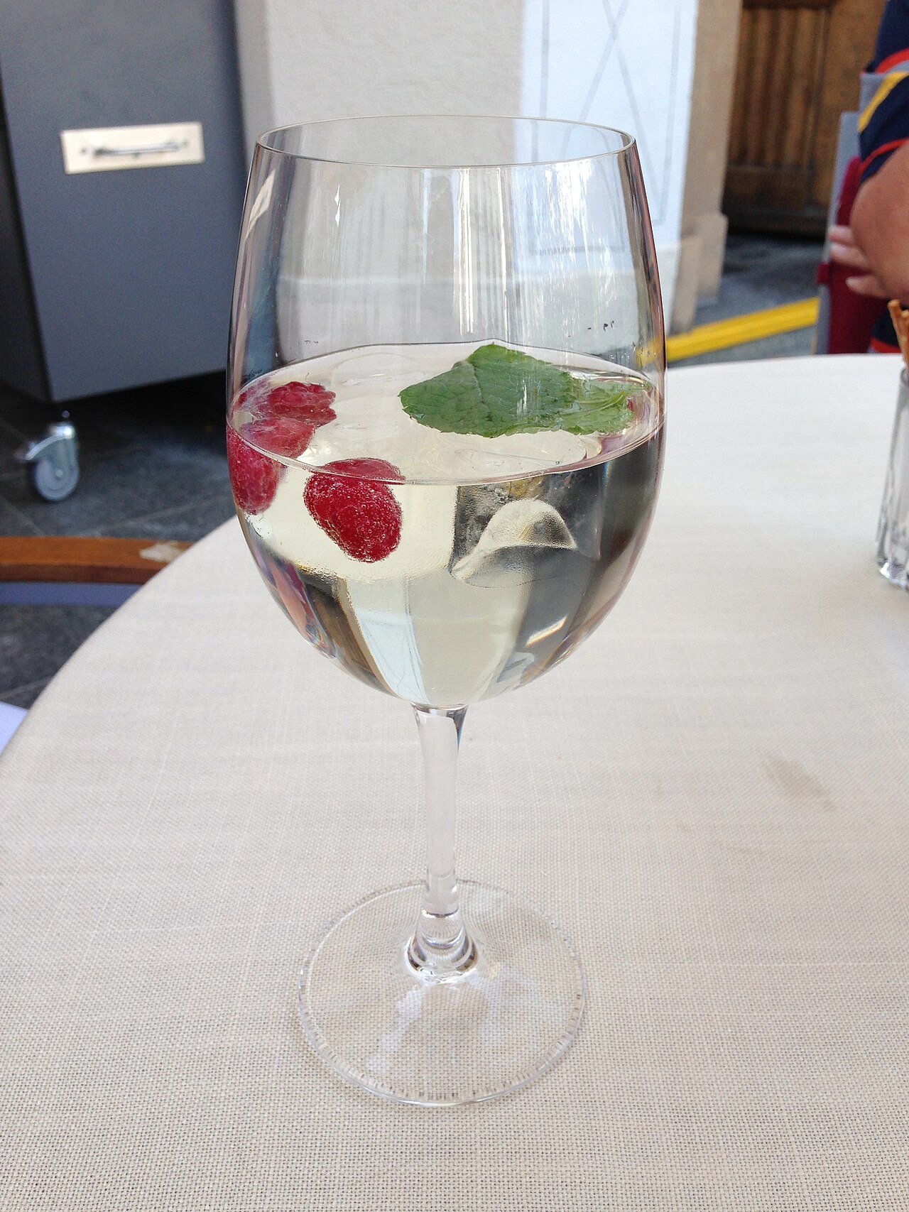 A Hugo spritz cocktail garnished with fresh mint and lime in a large wine glass