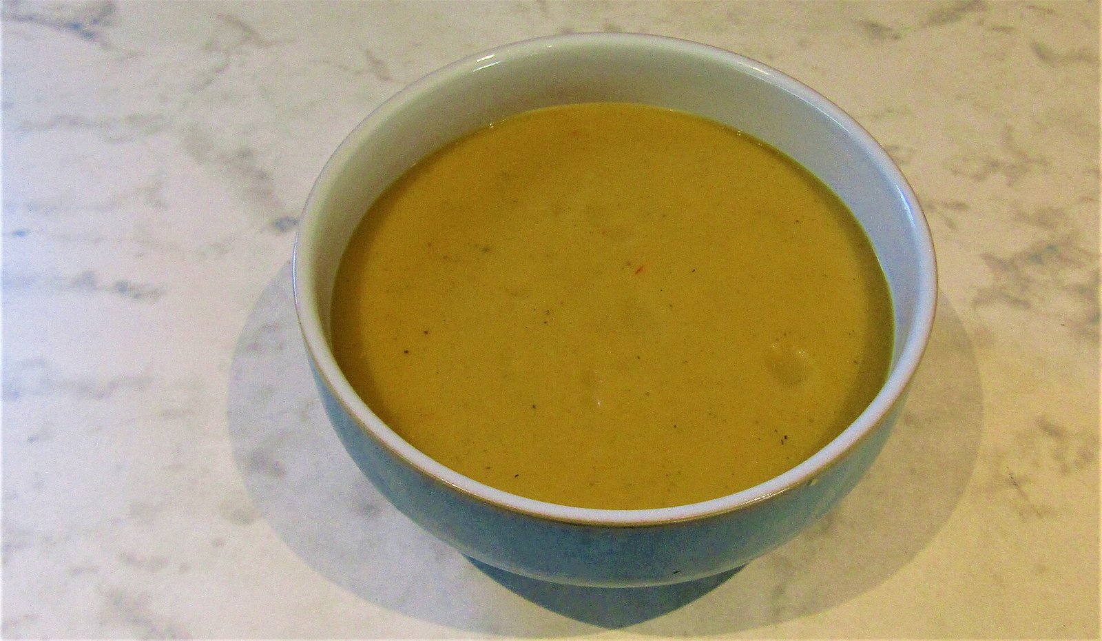 Bowl of creamy pumpkin curry soup garnished with coconut swirl and coriander