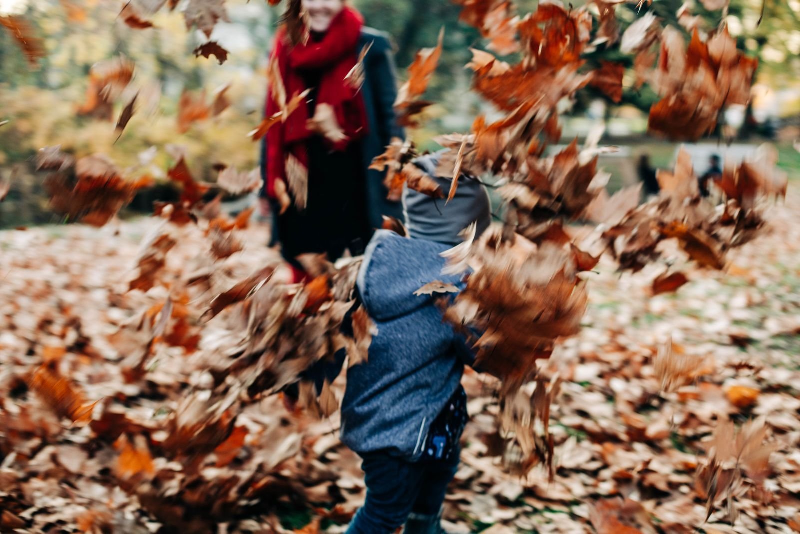 Joyful child running through colourful autumn leaves in a sunny park
