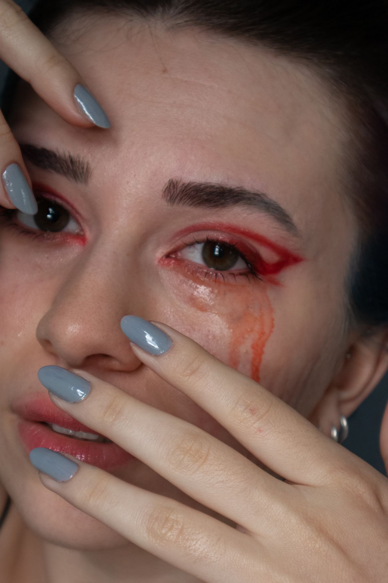 Bold red eye makeup with manicured nails in a striking close-up