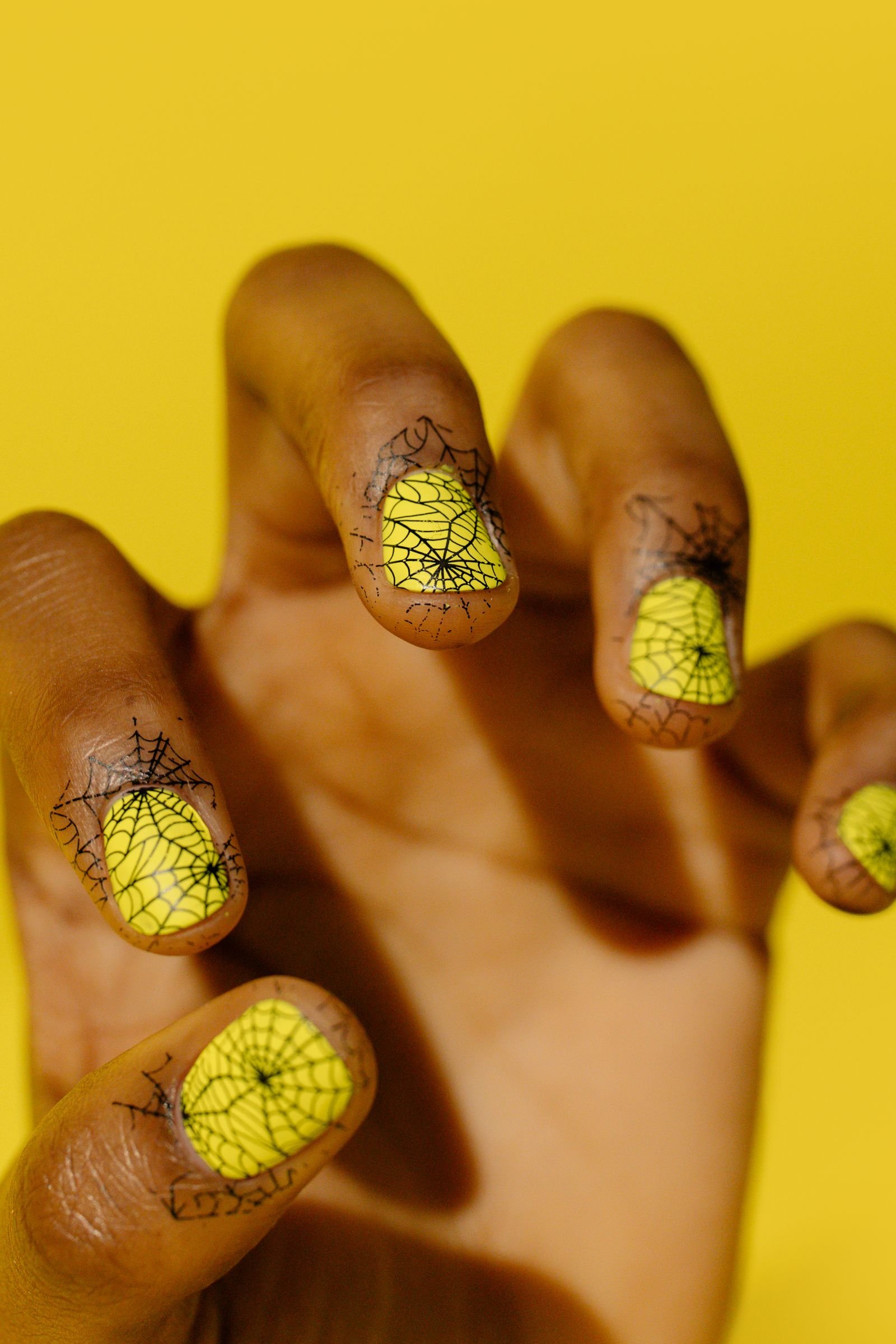 Black spiderweb nail design with yellow and black goth cat eye accents