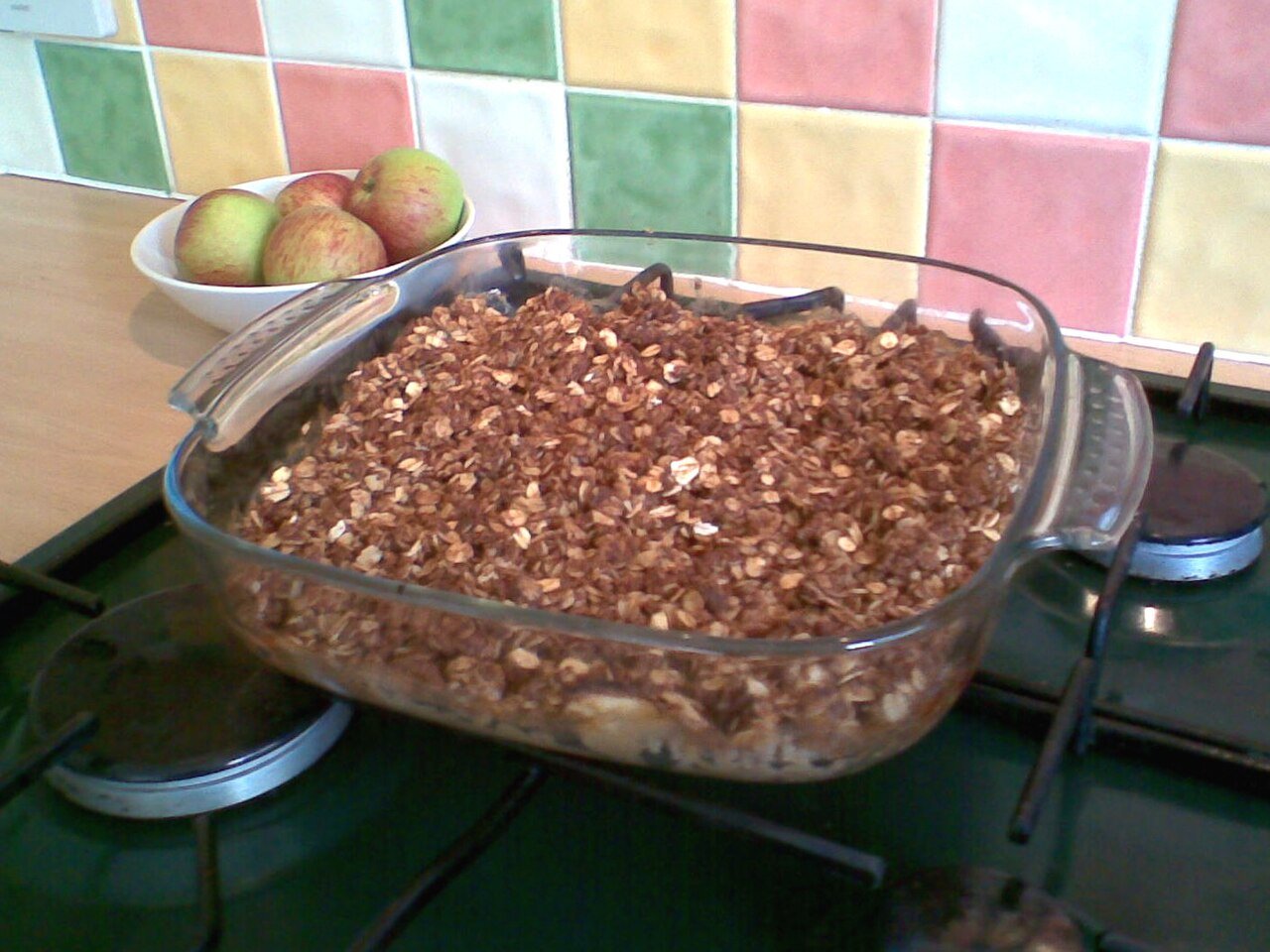 The oat topping spread thick over the fruit, turning golden as it bakes