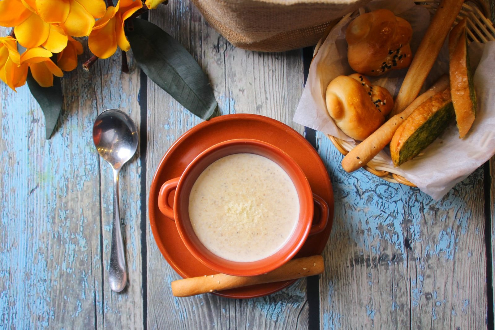 Large pot of soup with breadsticks and rolls on rustic wooden table