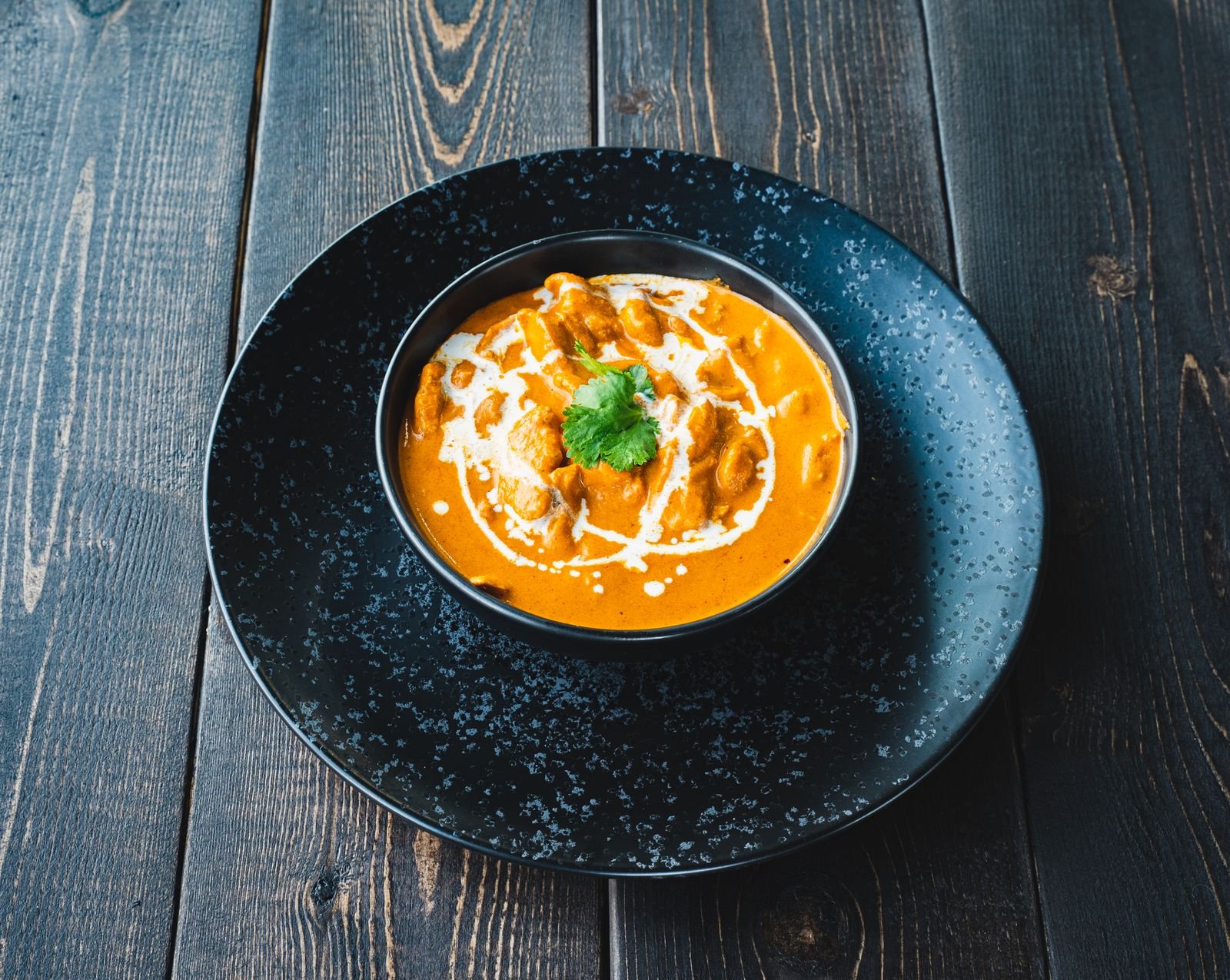 Creamy soup in ceramic bowl on rustic wooden table topped with coriander