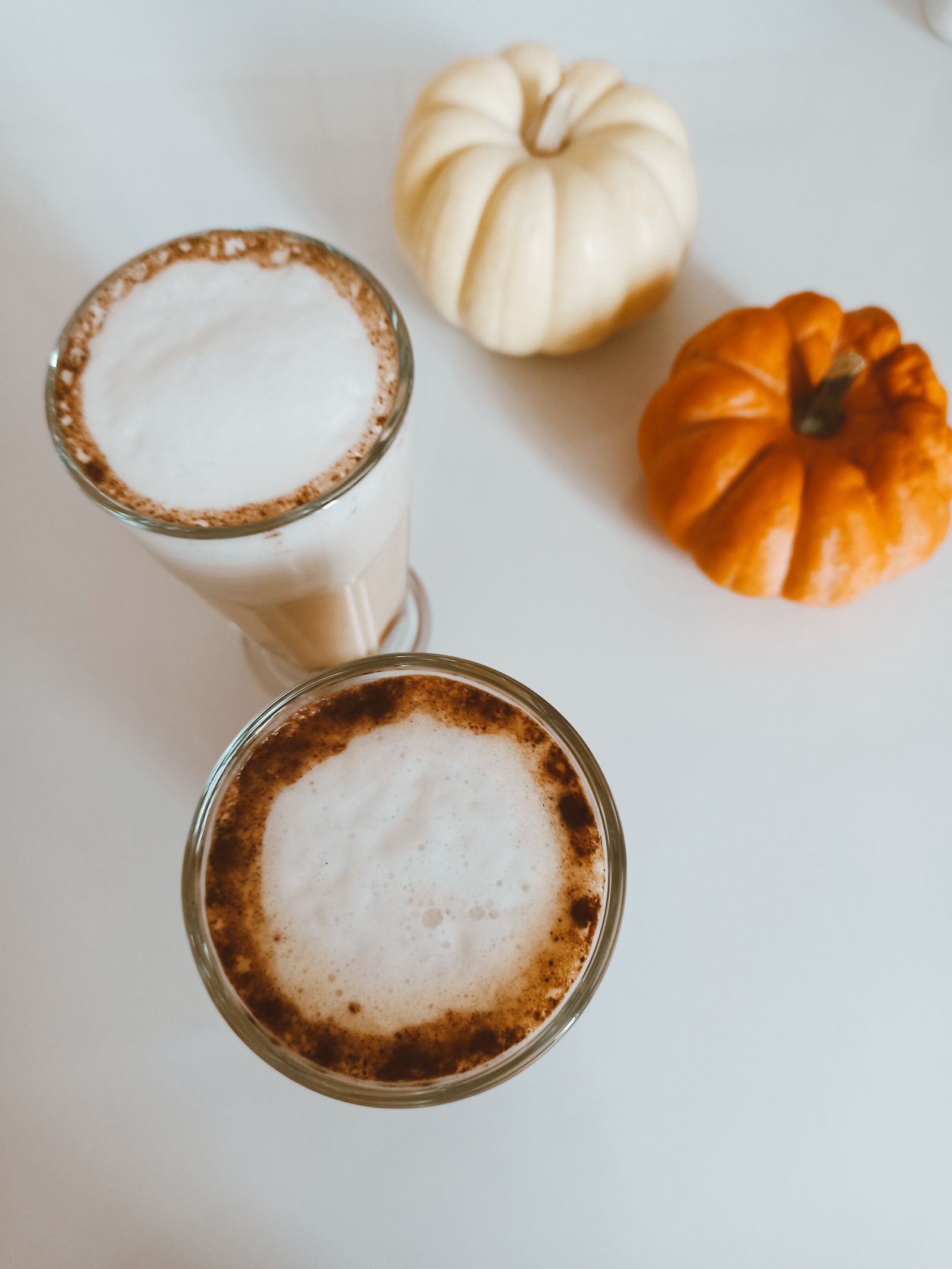 Pumpkin spice latte with foam served beside autumn baked treats