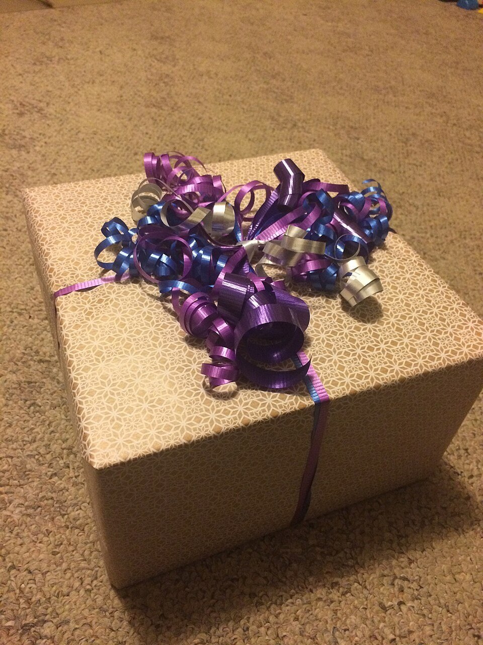 A person wrapping a gift carefully with paper and ribbon