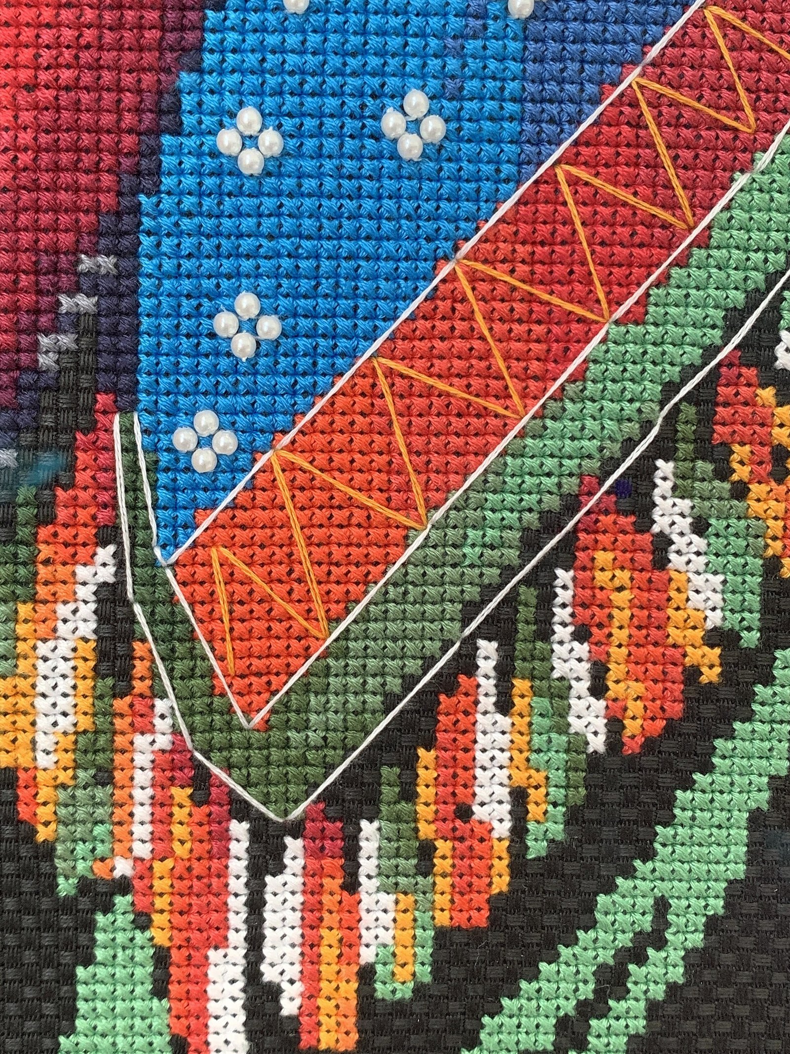 Hands stitching an autumn cross stitch pattern in an embroidery hoop