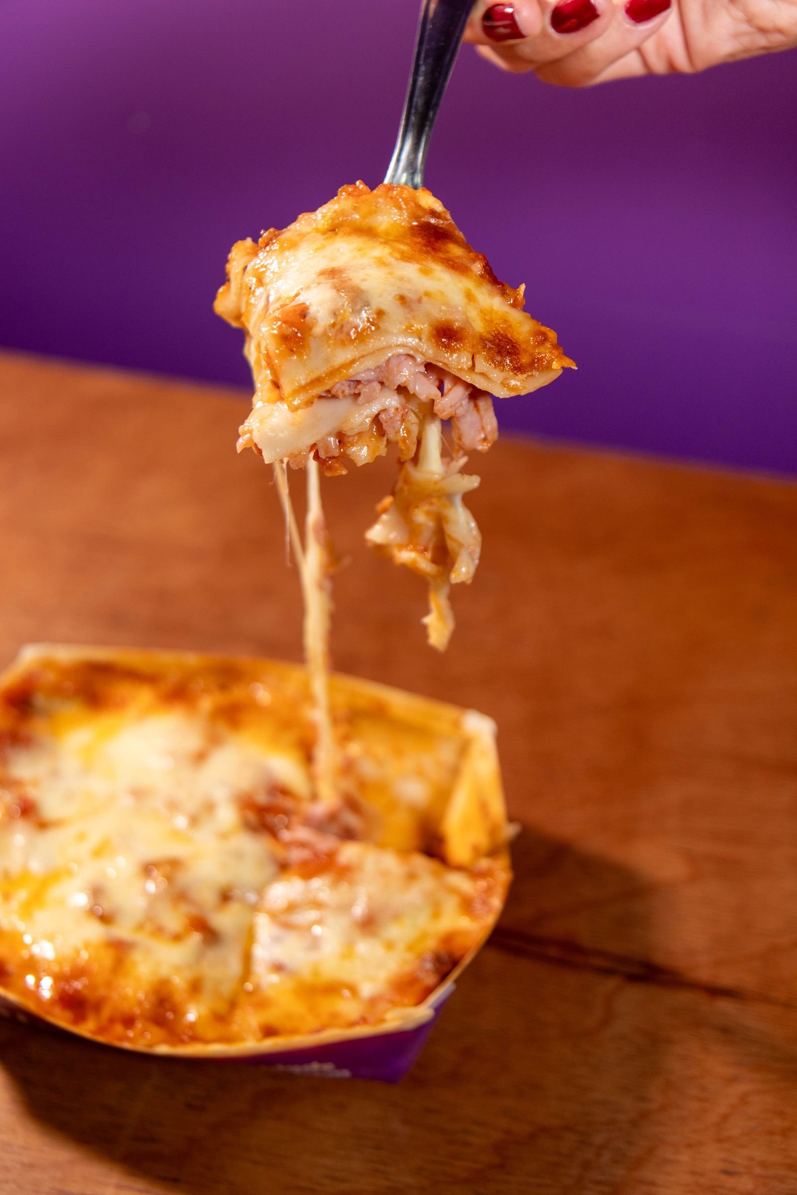 Slice of layered lasagna being lifted from a baking dish
