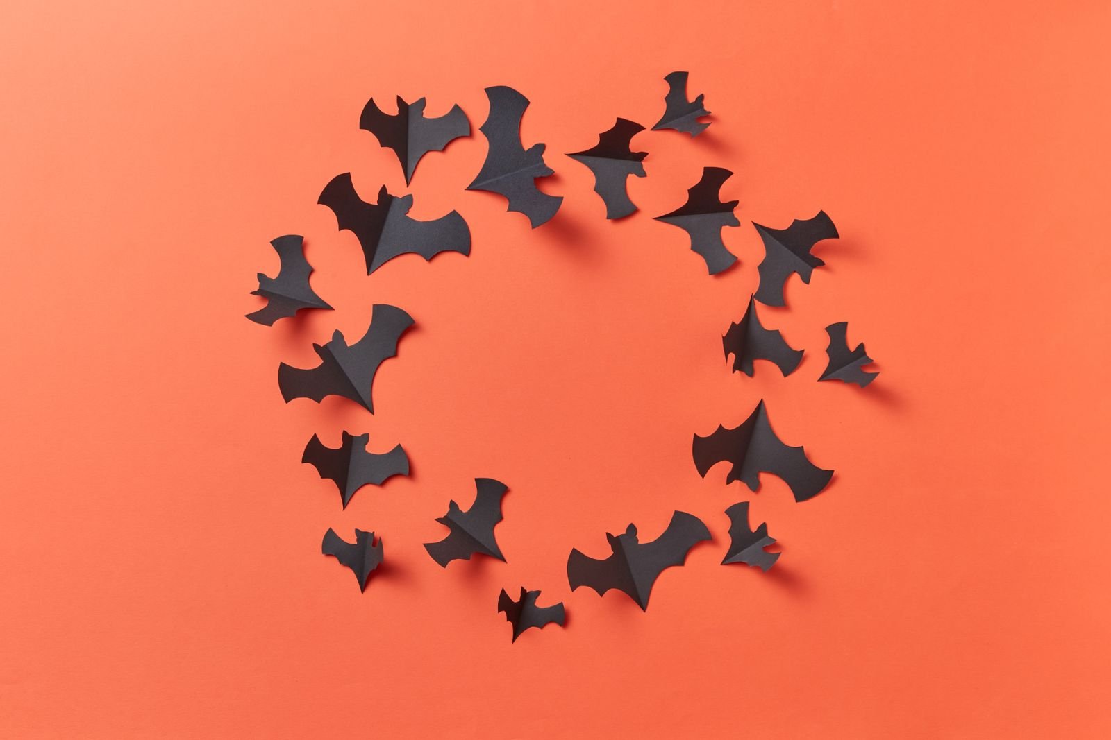 Black paper bats arranged on an orange background for Halloween decoration