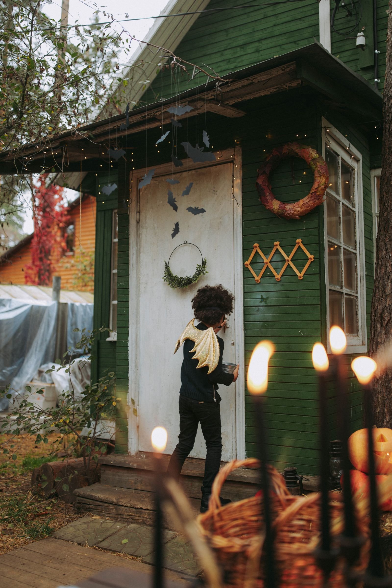 Child in costume approaching a decorated green house ready to trick-or-treat