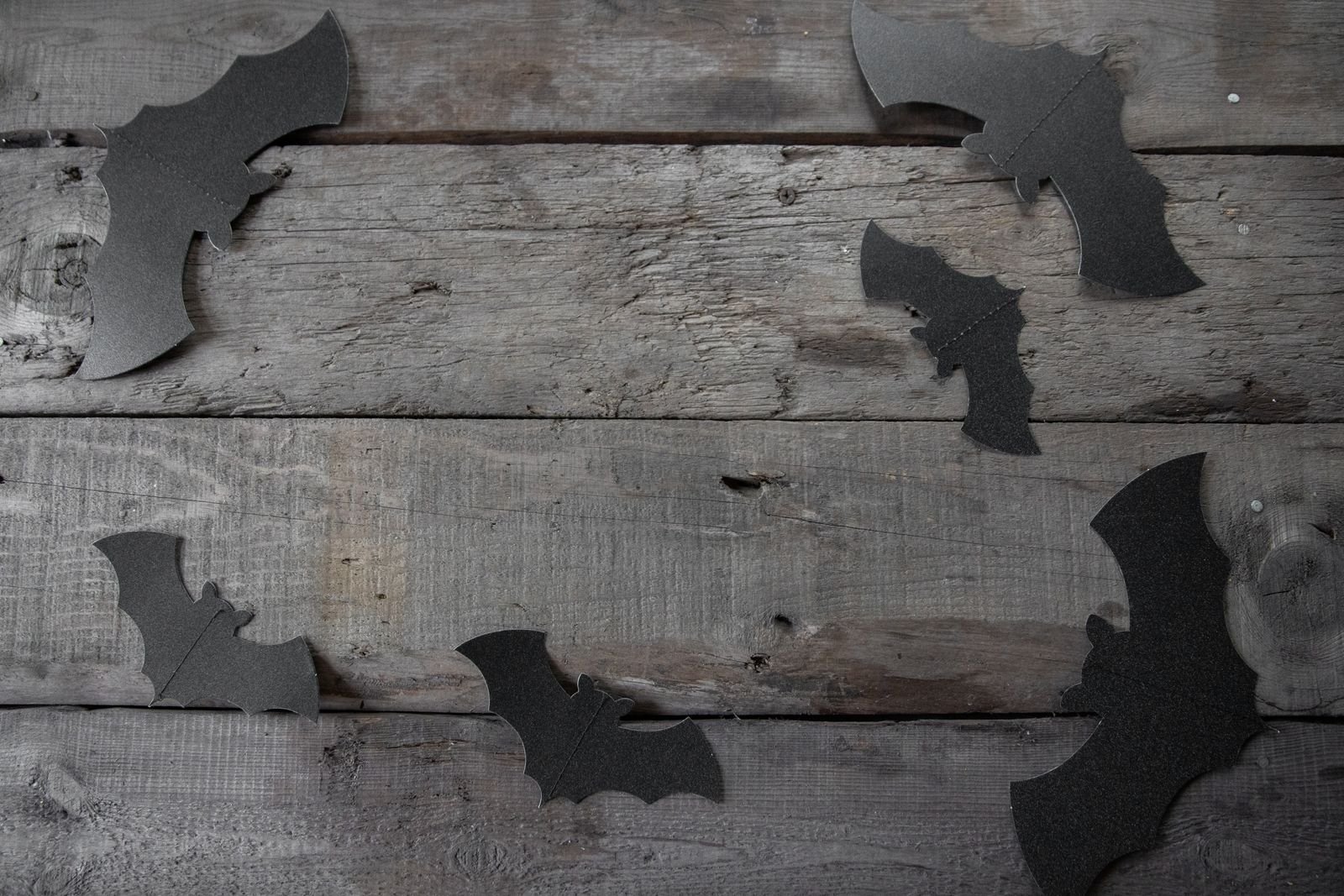 Dark bat silhouettes on a rustic wooden background for spooky Halloween decor