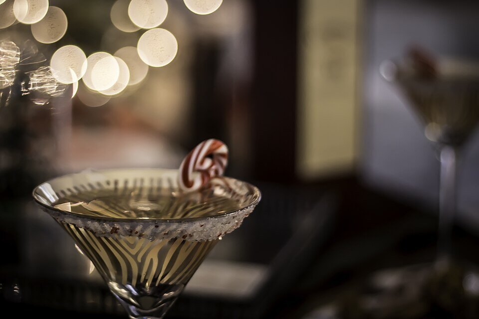A red cranberry martini garnished with cranberries and rosemary