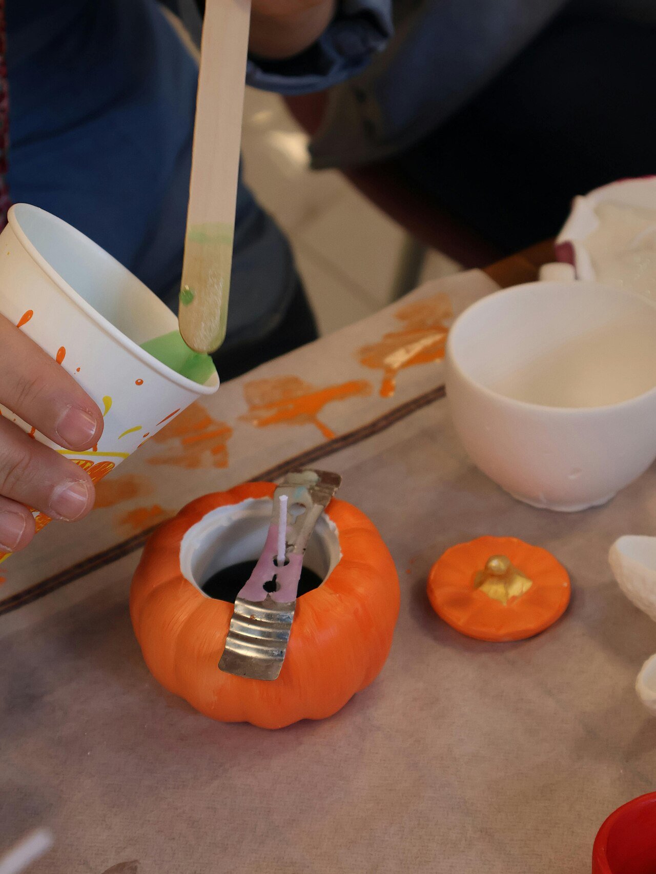 Hands crafting decorations with mini pumpkins