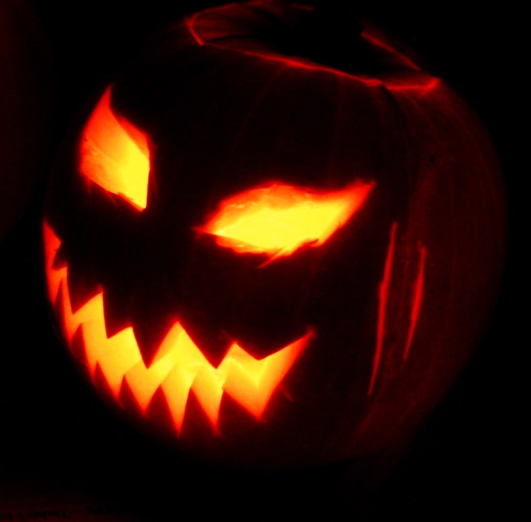 Carved Halloween pumpkin face glowing in the dark