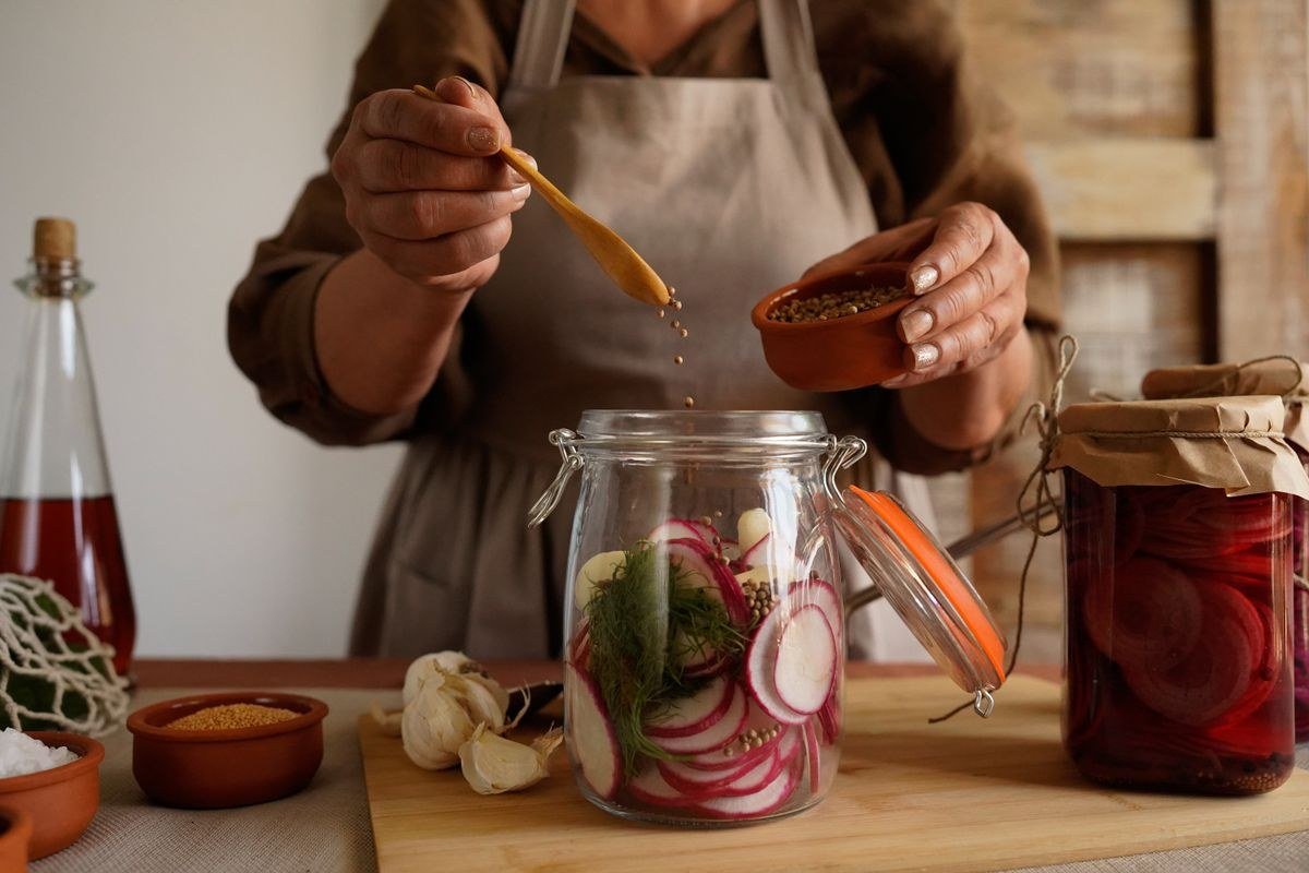 Packing sliced beets tightly into hot mason jars with a funnel