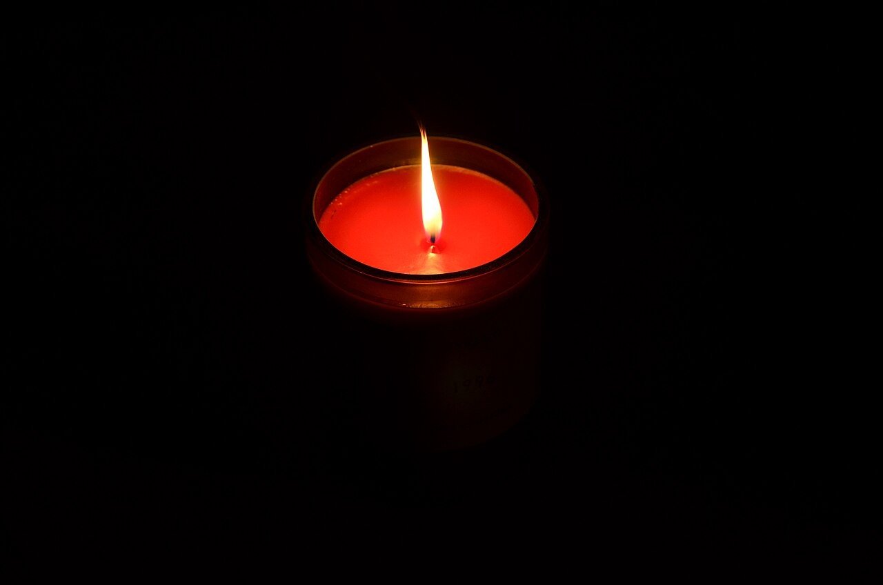 Lit red scented candle in the dark