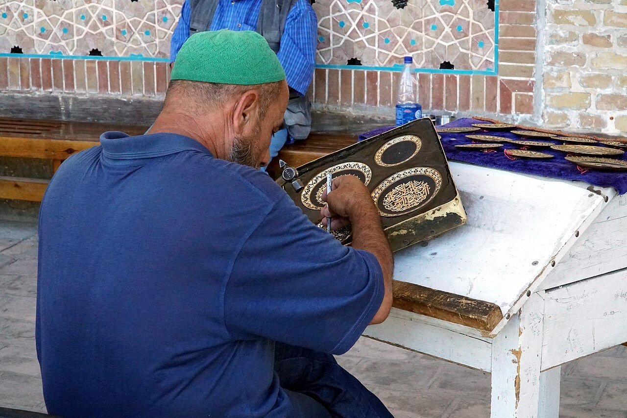 Craftsman engraving a metal plate in a workshop