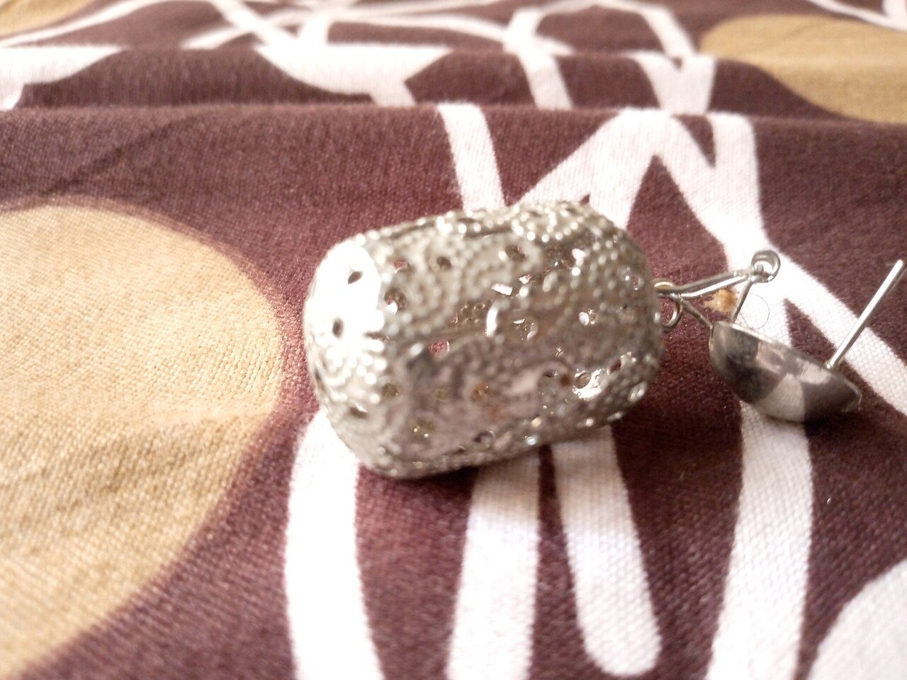 Single ornate earring on patterned fabric