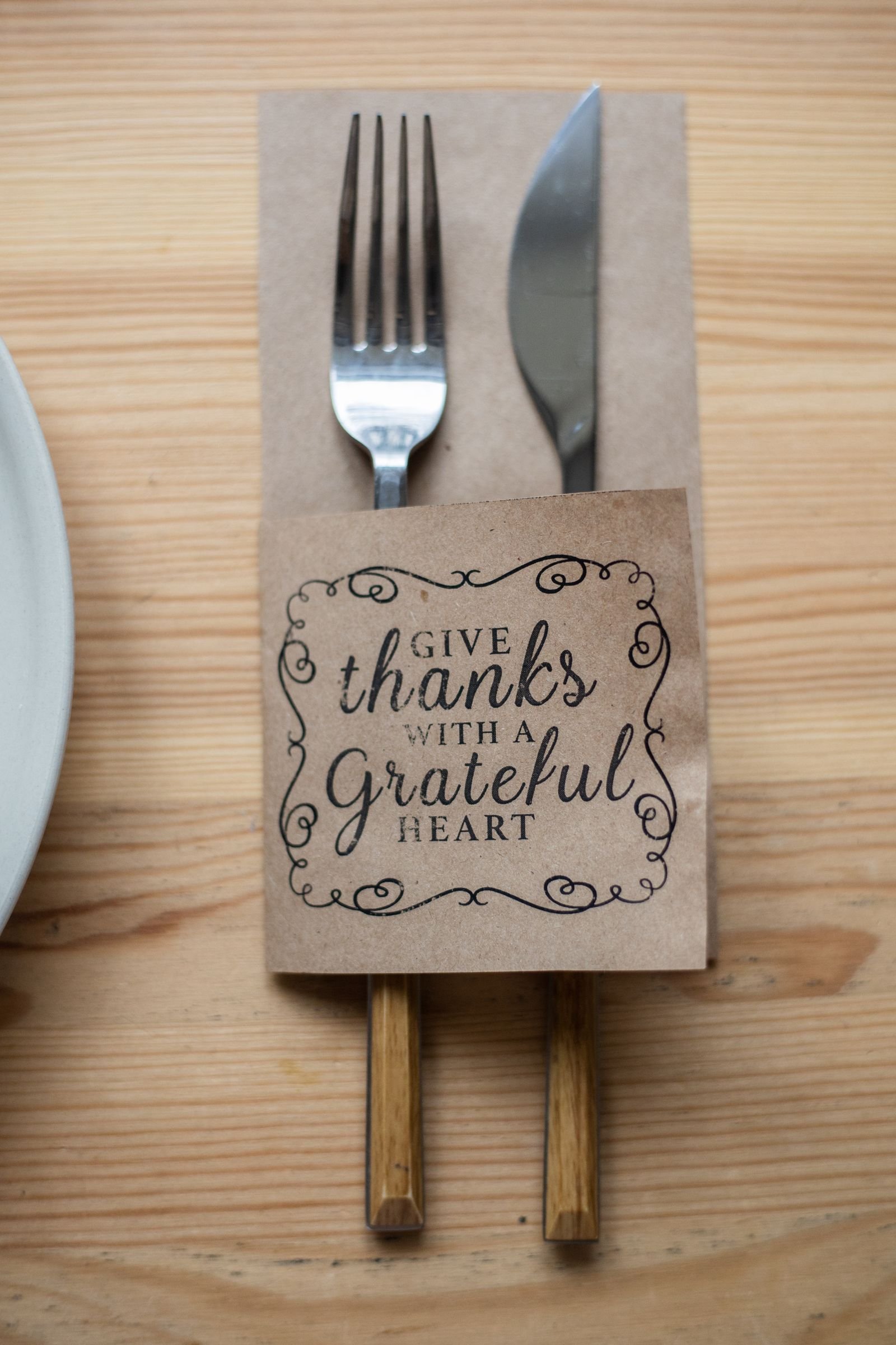 Give Thanks cutlery set in paper sleeve on a wooden family table