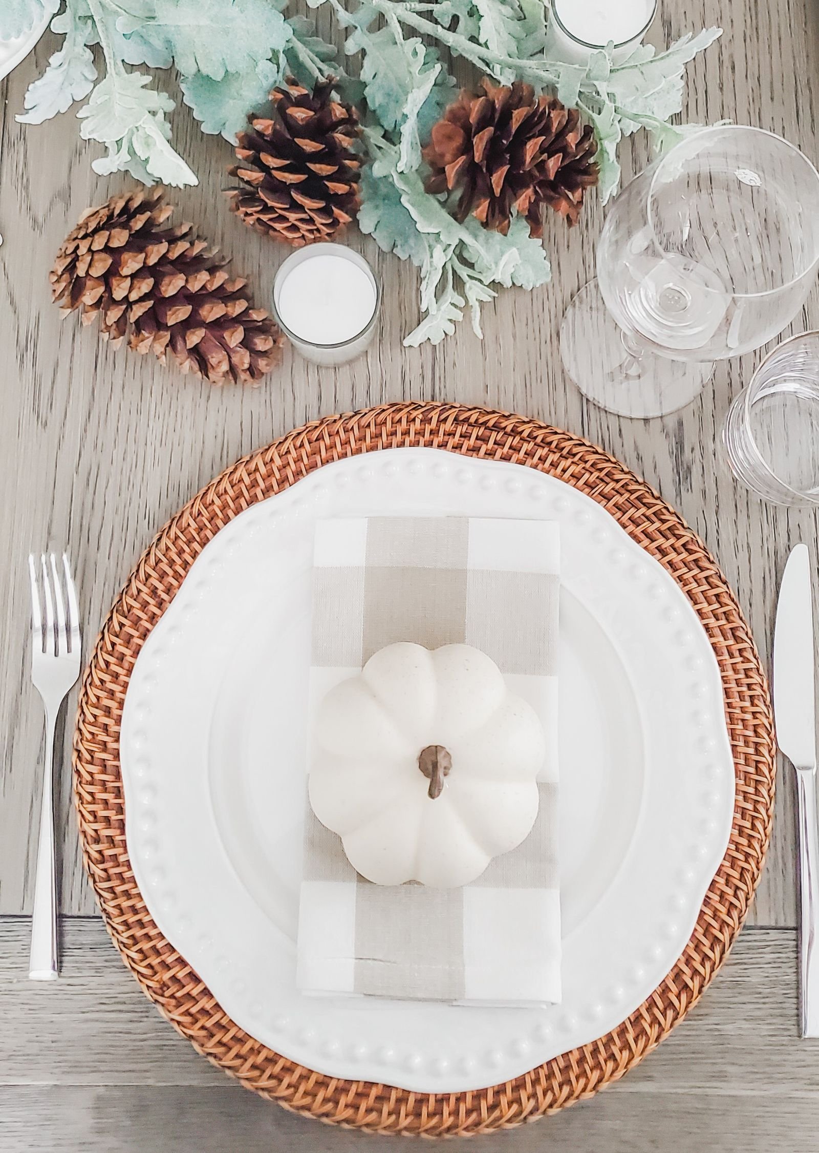 White pumpkin with pinecones and elegant place settings in candlelight
