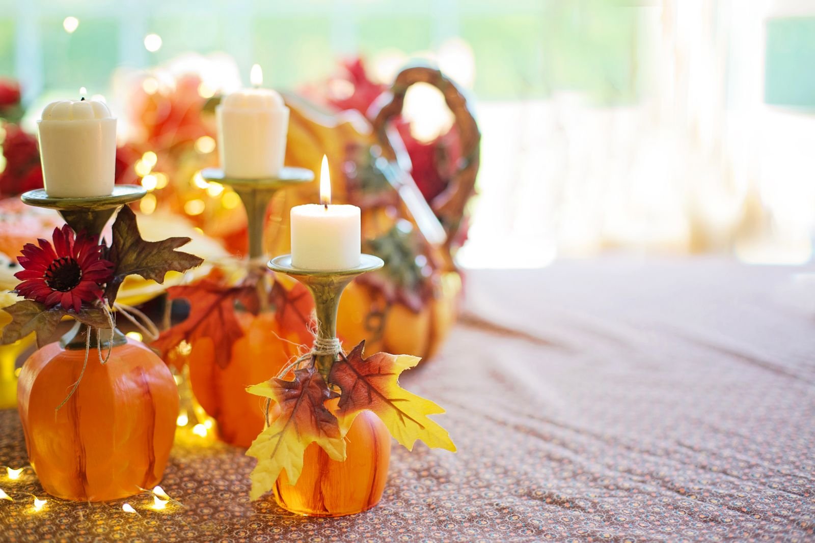 Warm autumn centrepiece with pumpkins, candle holders and fall leaves